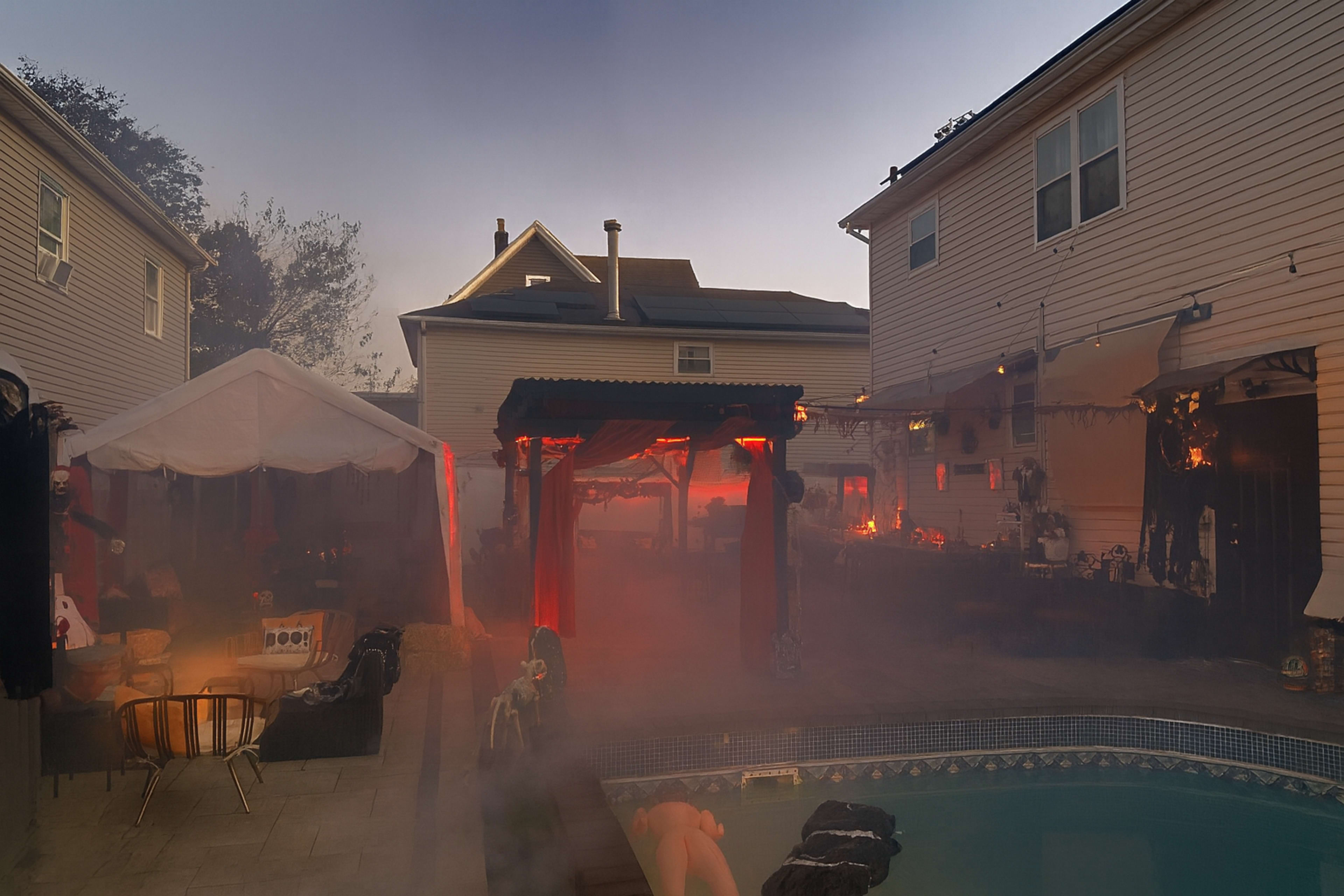 The scene shows a backyard party setup with decorative tents, glowing lights, and a pool surrounded by fog.