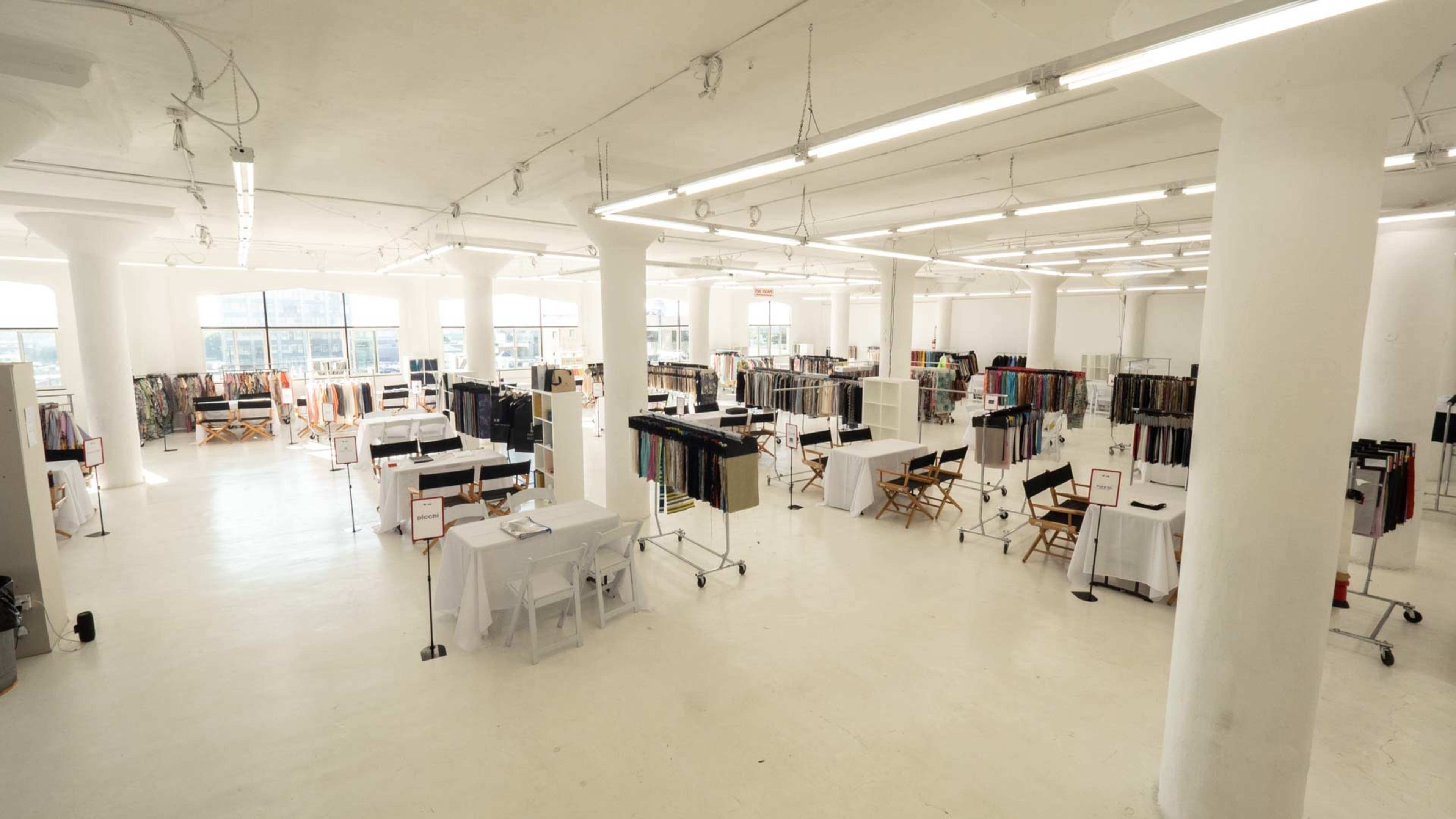 A spacious, brightly lit event space with rows of tables and displays set up for a fabric exhibition.