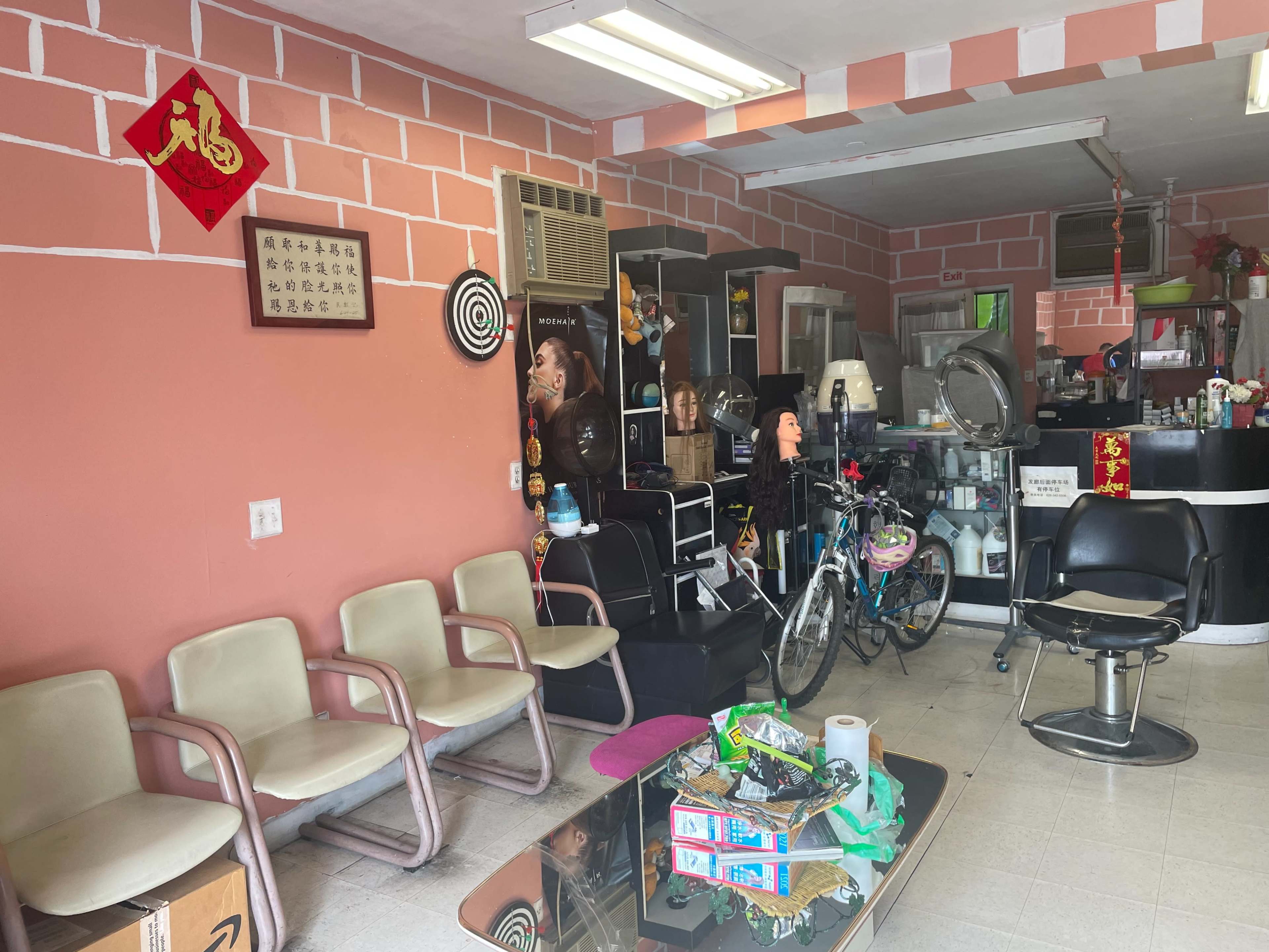A small, brightly colored salon with chairs for waiting customers and various hairdressing equipment on display.