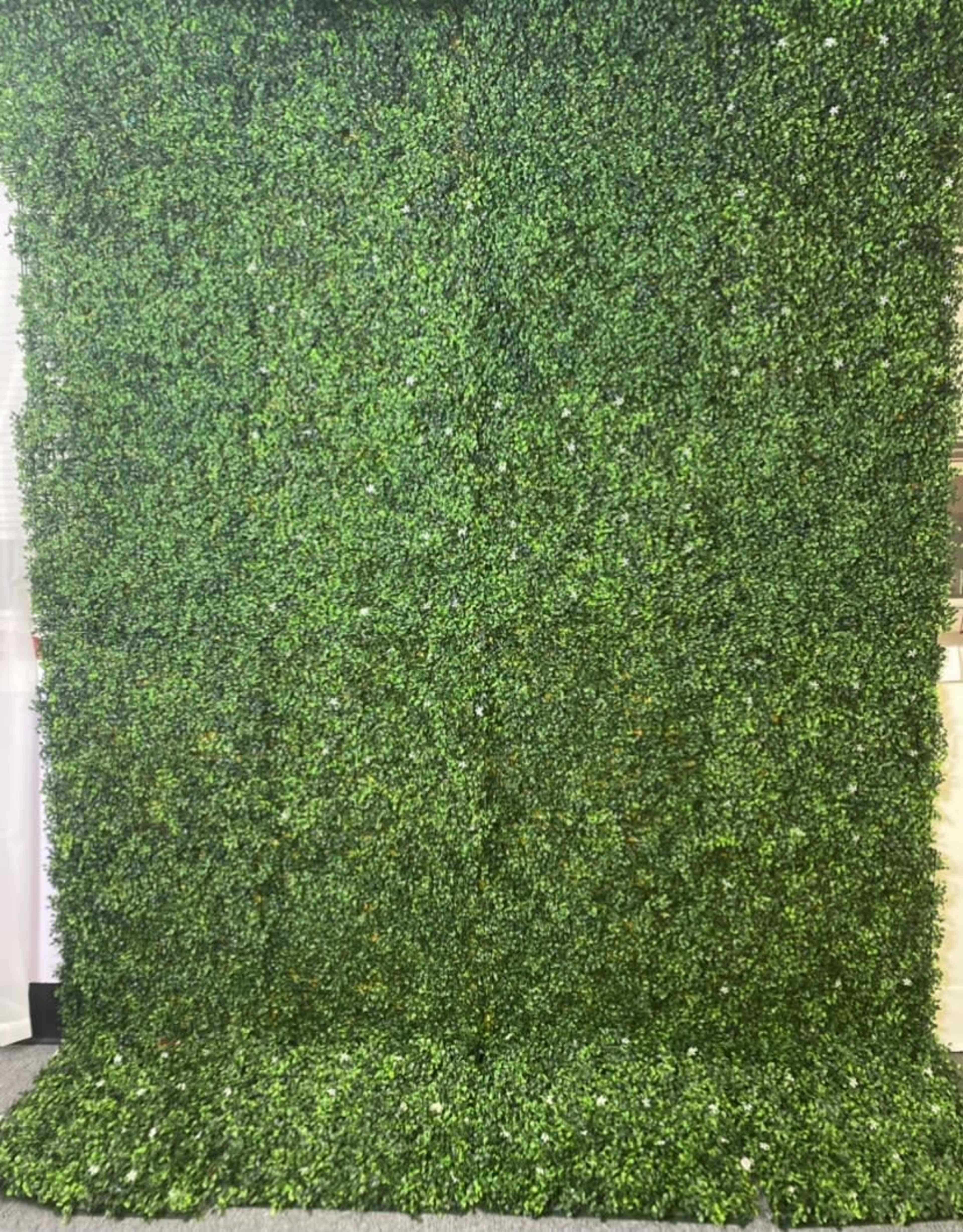 A large wall covered with lush, green artificial foliage.