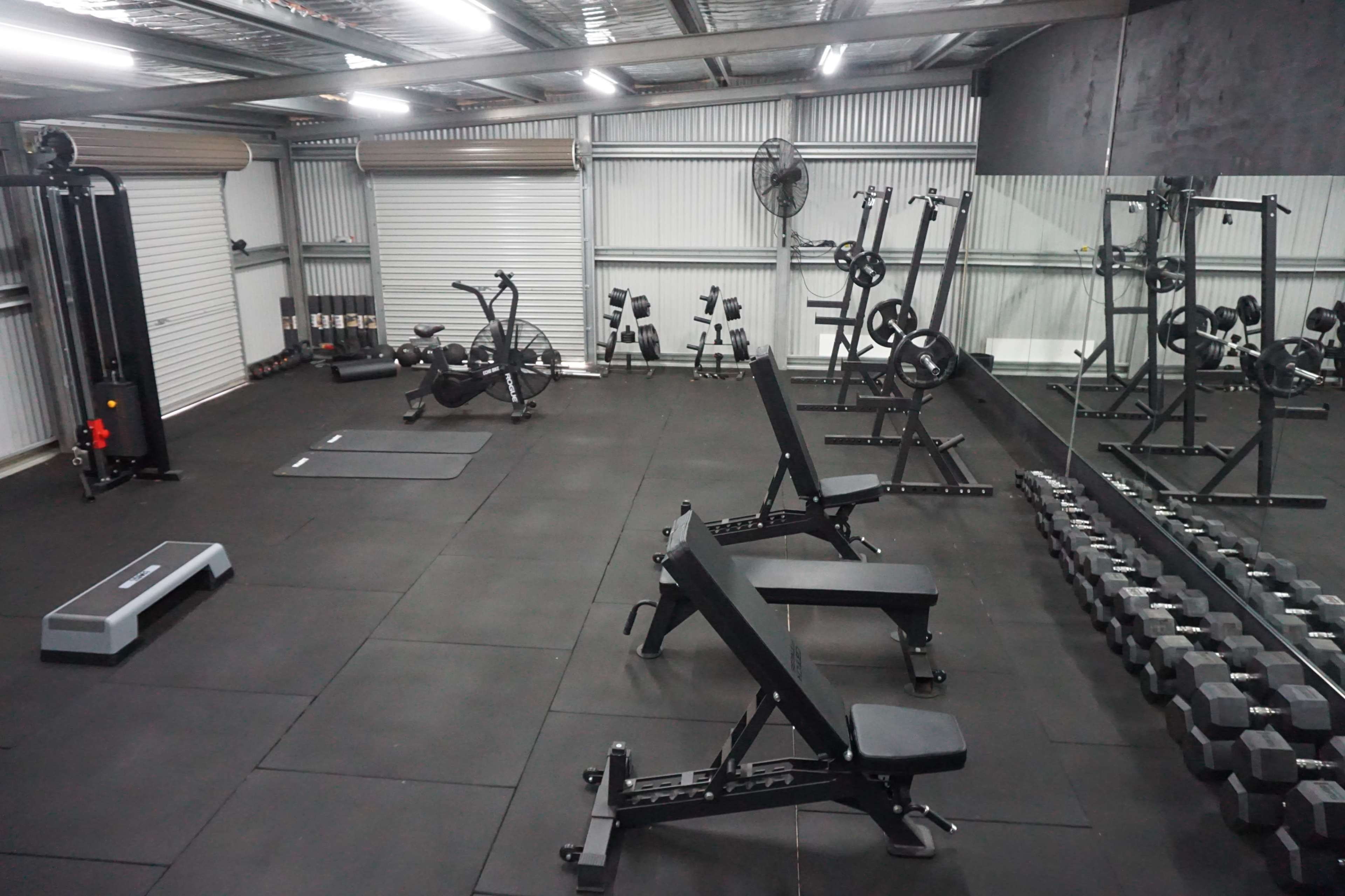 A fitness gym equipped with exercise machines, weights, and a mirror on one wall.
