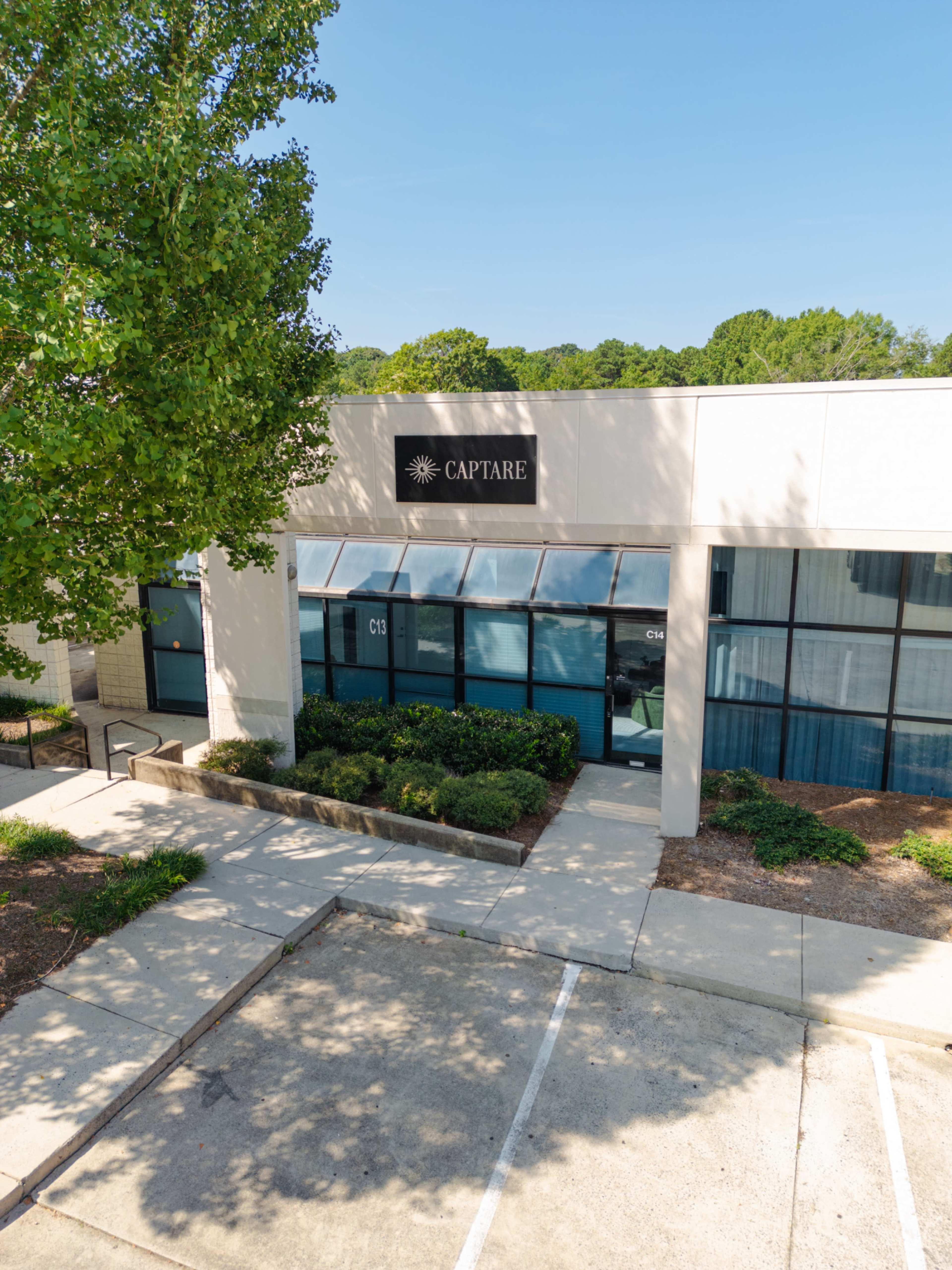 The image shows a modern office building with large windows and a sign that reads "CAPTARE" above the entrance.