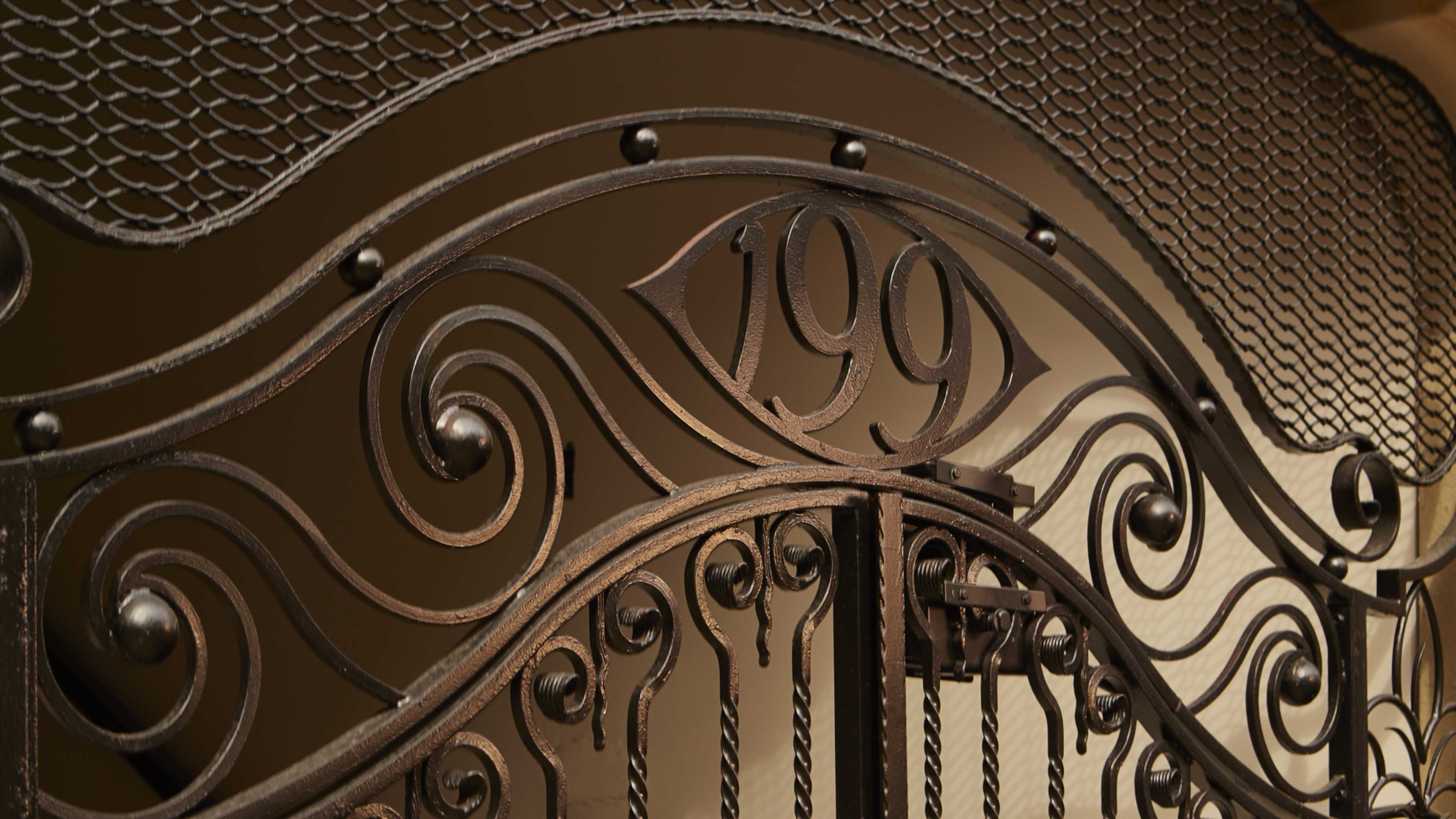 An ornate metal gate with intricate scrolling designs and the number "199" prominently displayed in the center.
