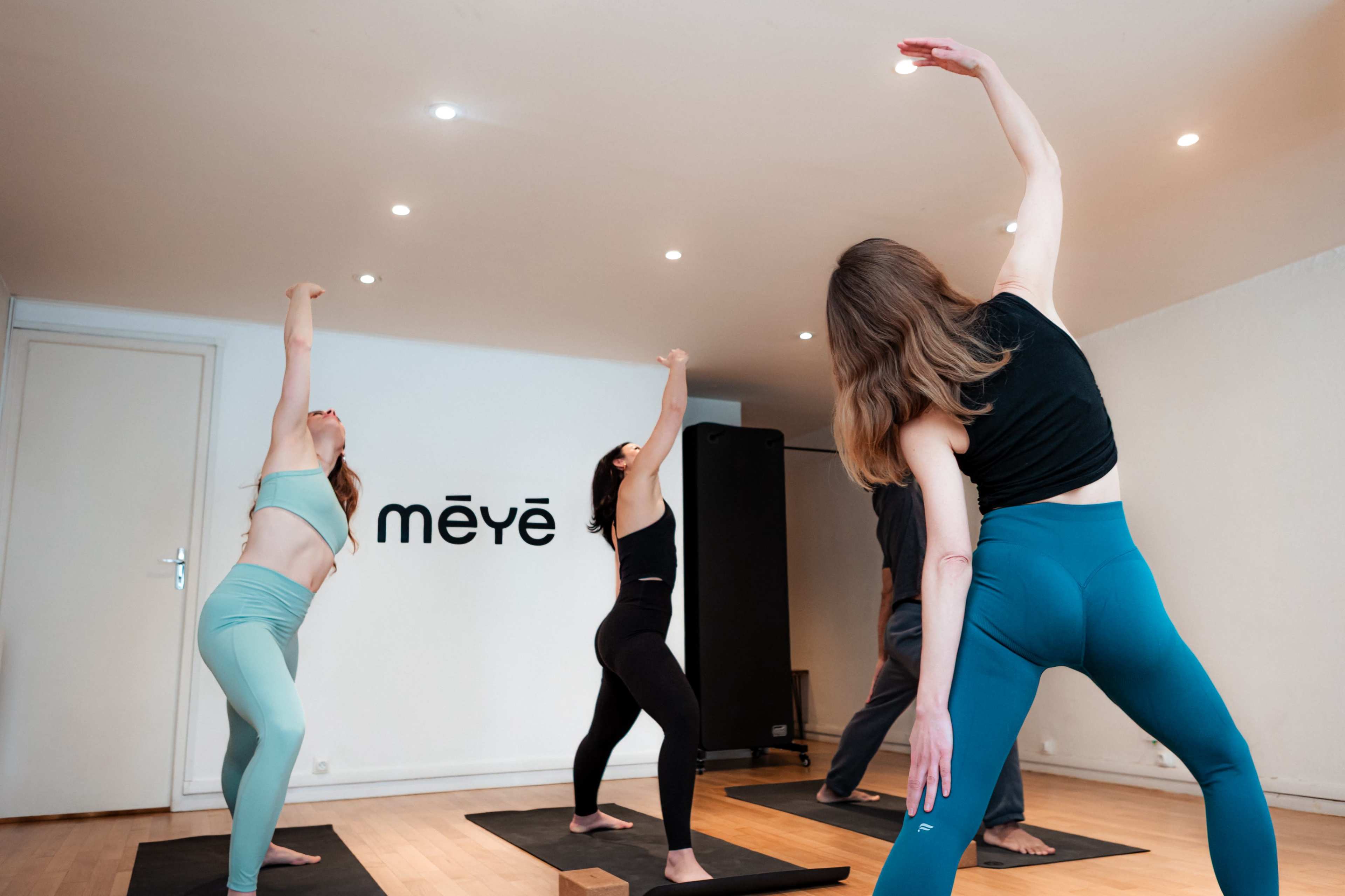A group of four individuals are practicing yoga in a studio, each adopting different poses on yoga mats.