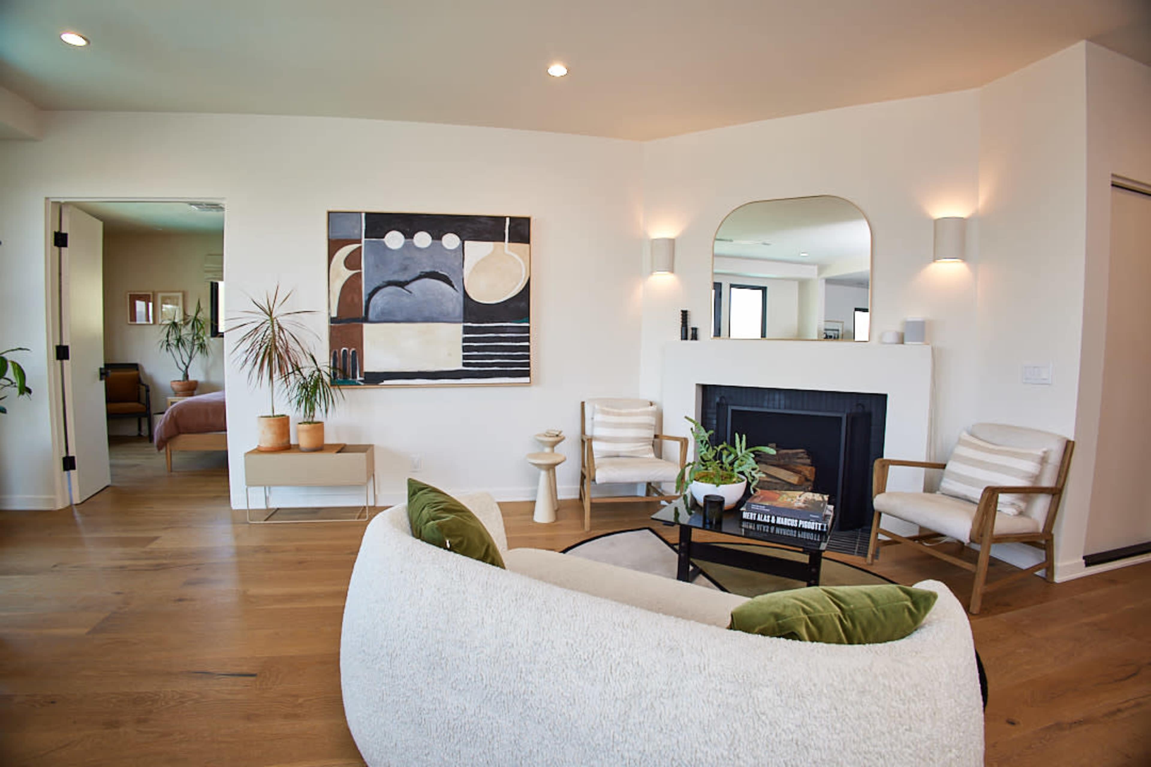 A modern living room features a cozy seating arrangement, a fireplace, and a large abstract painting on the wall.