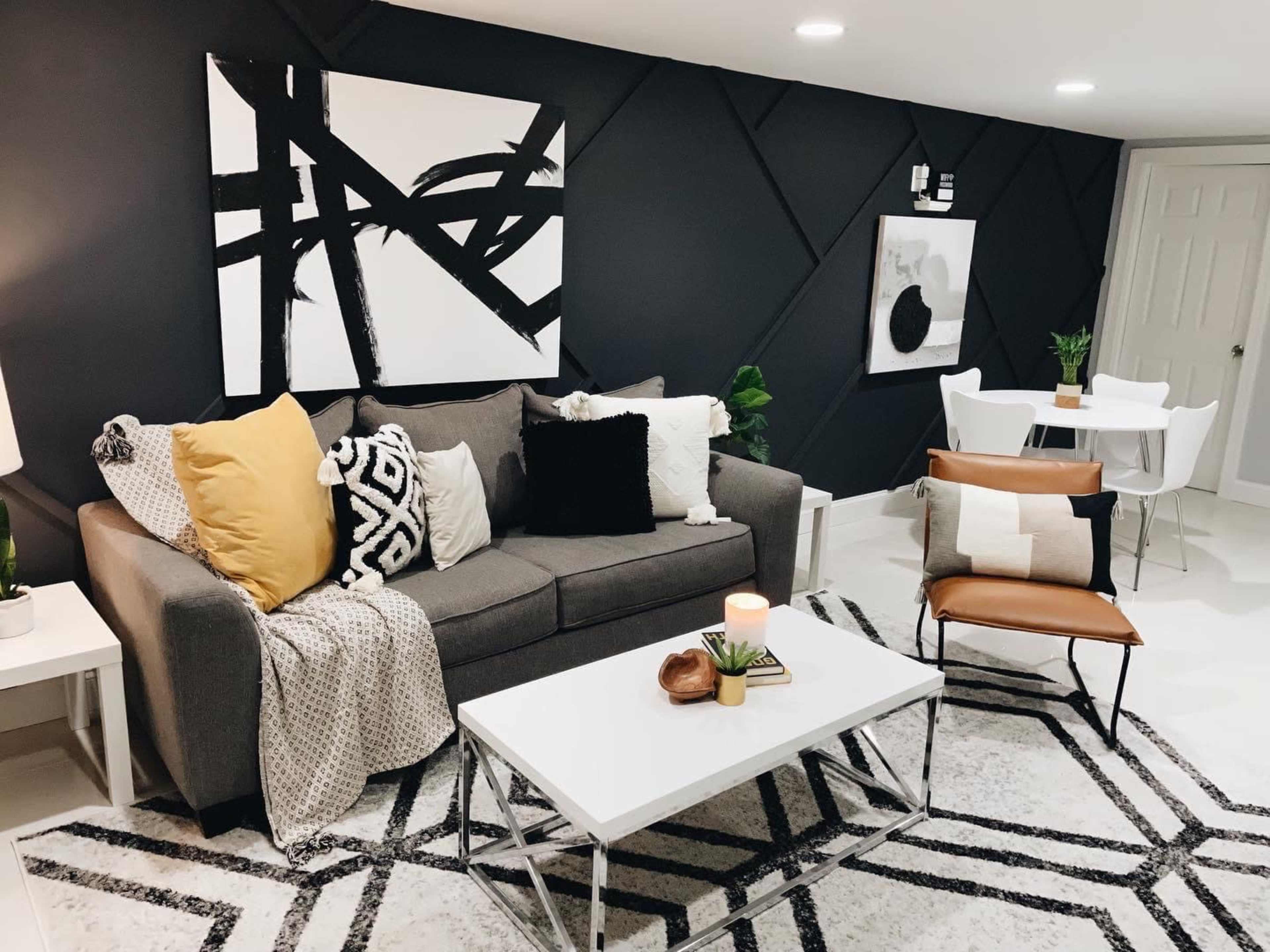 A modern living room with a gray sofa, decorative pillows, a coffee table, and a small dining area featuring a round table and chairs.