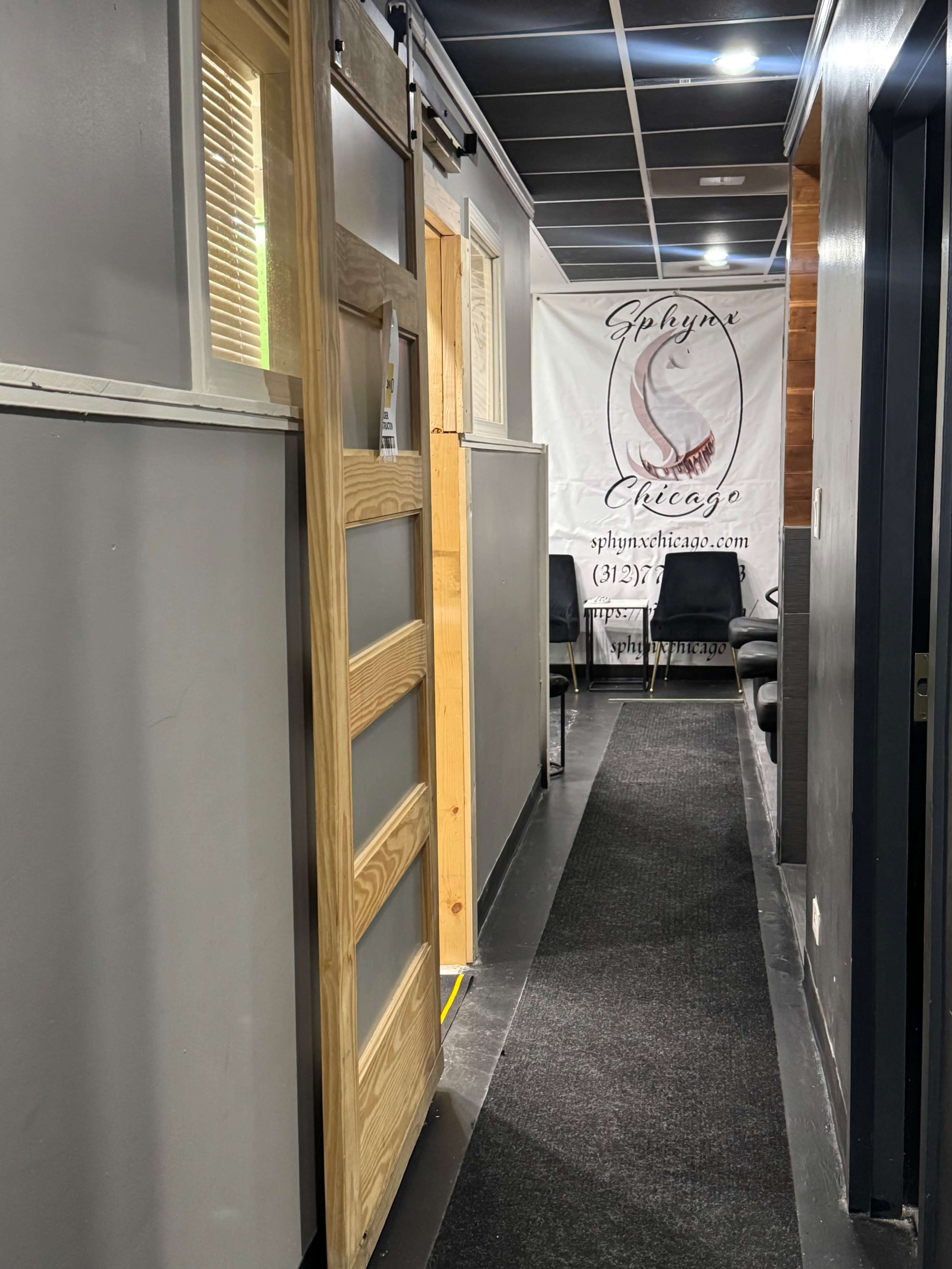 The image depicts a narrow hallway leading to a door, with a banner displaying "Splynx Chicago" on the wall and chairs lining the right side.