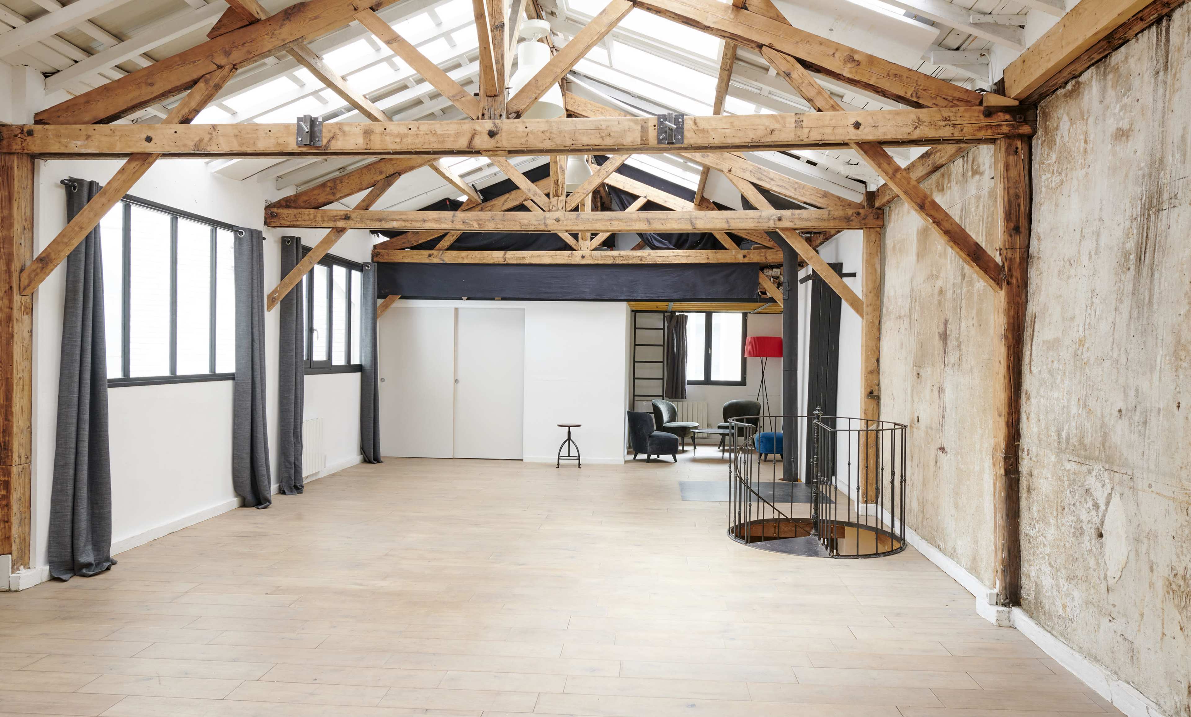 A spacious, minimalist interior with wooden beams, large windows, and a blend of modern and rustic design elements.