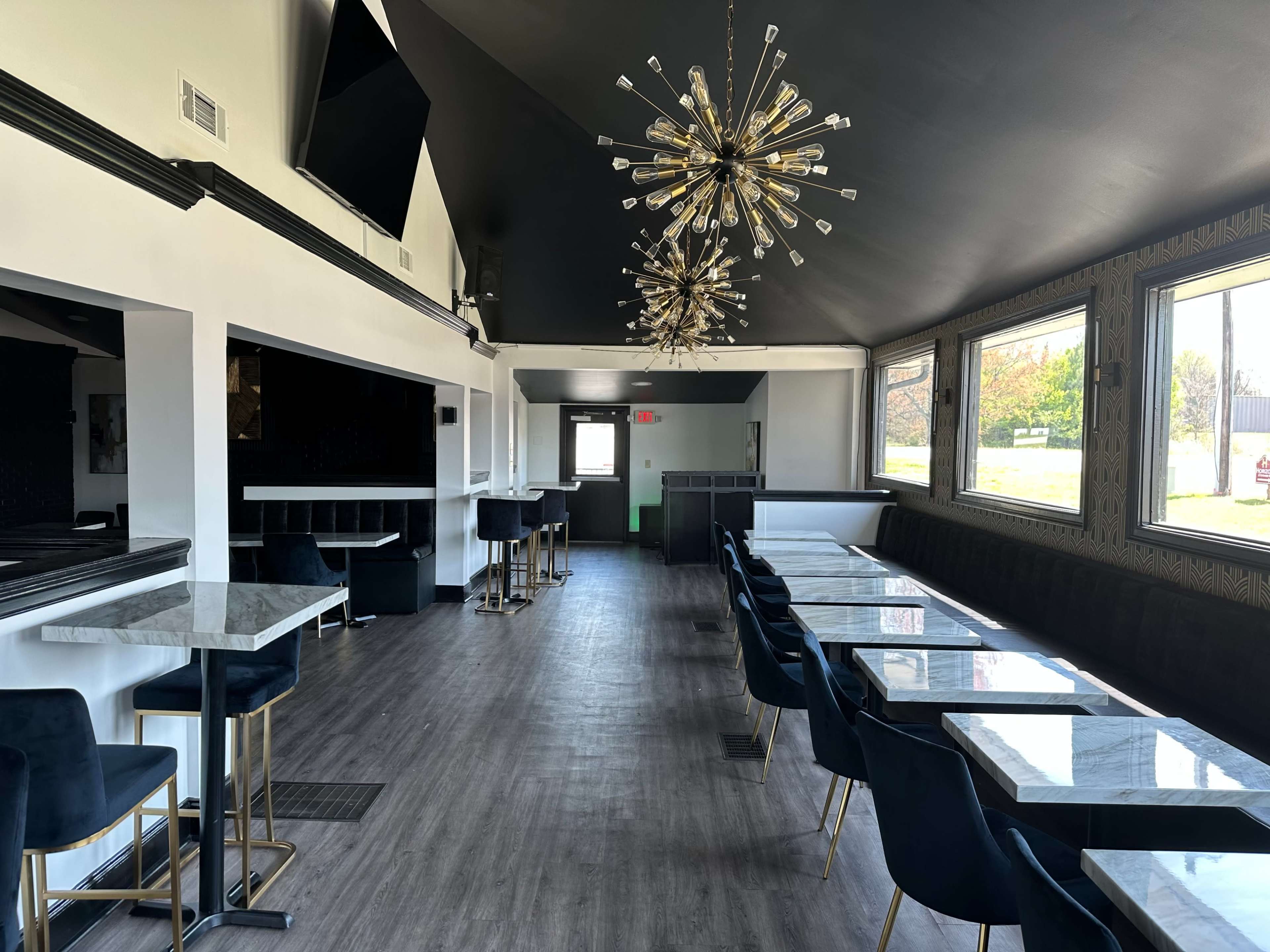 The image shows the interior of a modern dining area with marble-topped tables, dark blue chairs, and contemporary lighting fixtures.