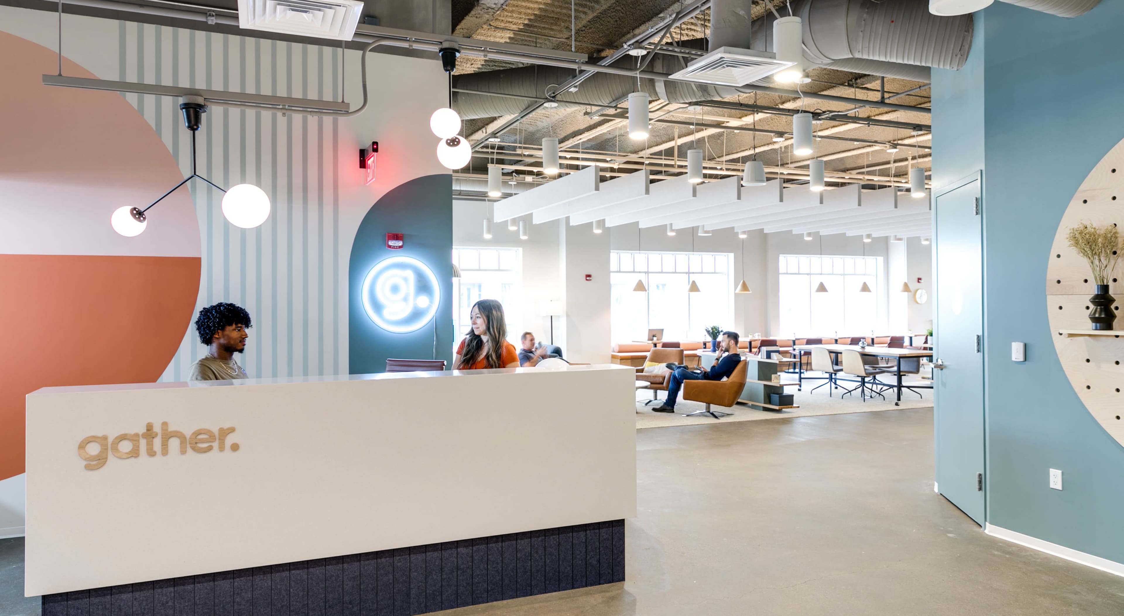 A modern office reception area with a front desk labeled "gather." and a spacious coworking space in the background.