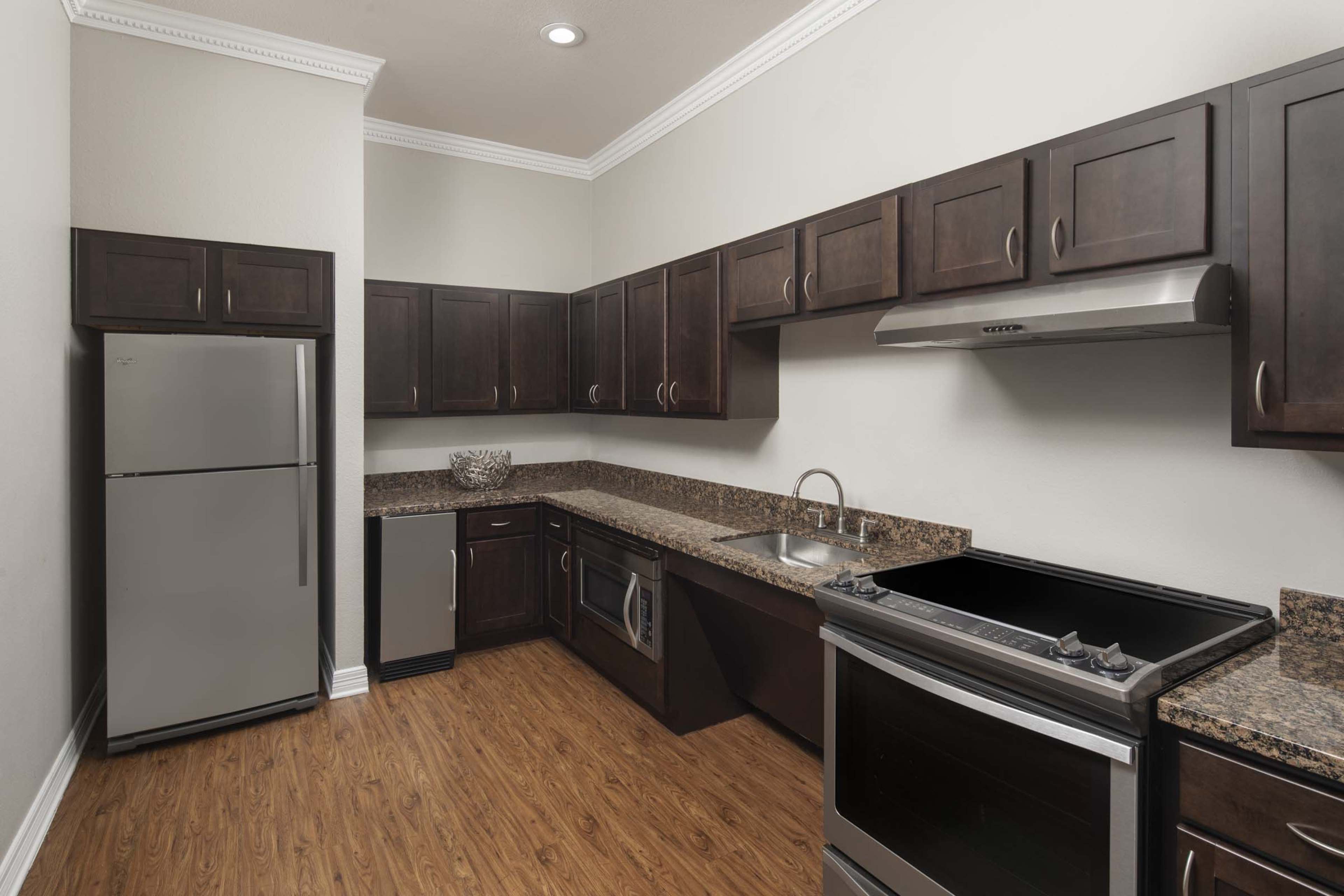 The kitchen features dark wood cabinets, stainless steel appliances, and a granite countertop.