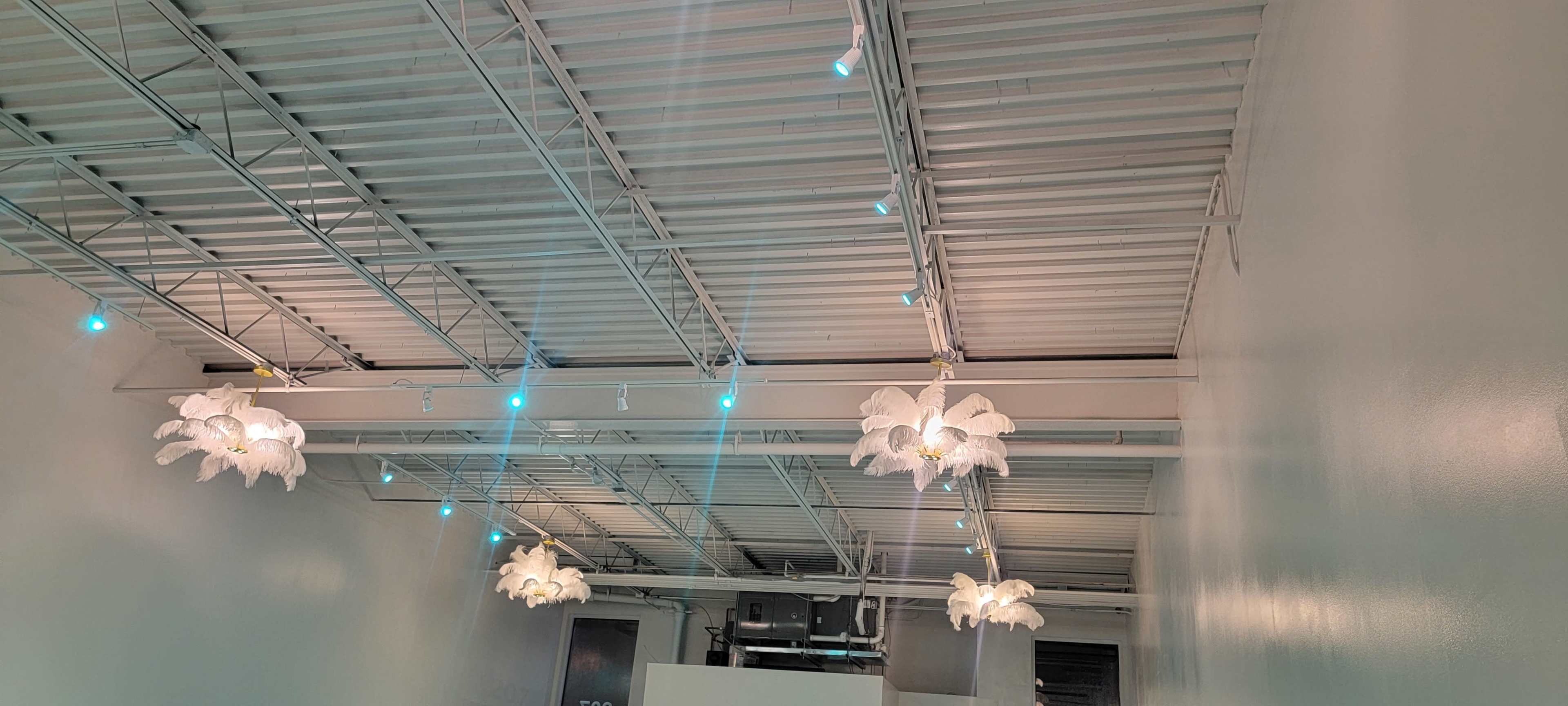 The image shows a modern interior with white walls and several decorative light fixtures hanging from the ceiling.