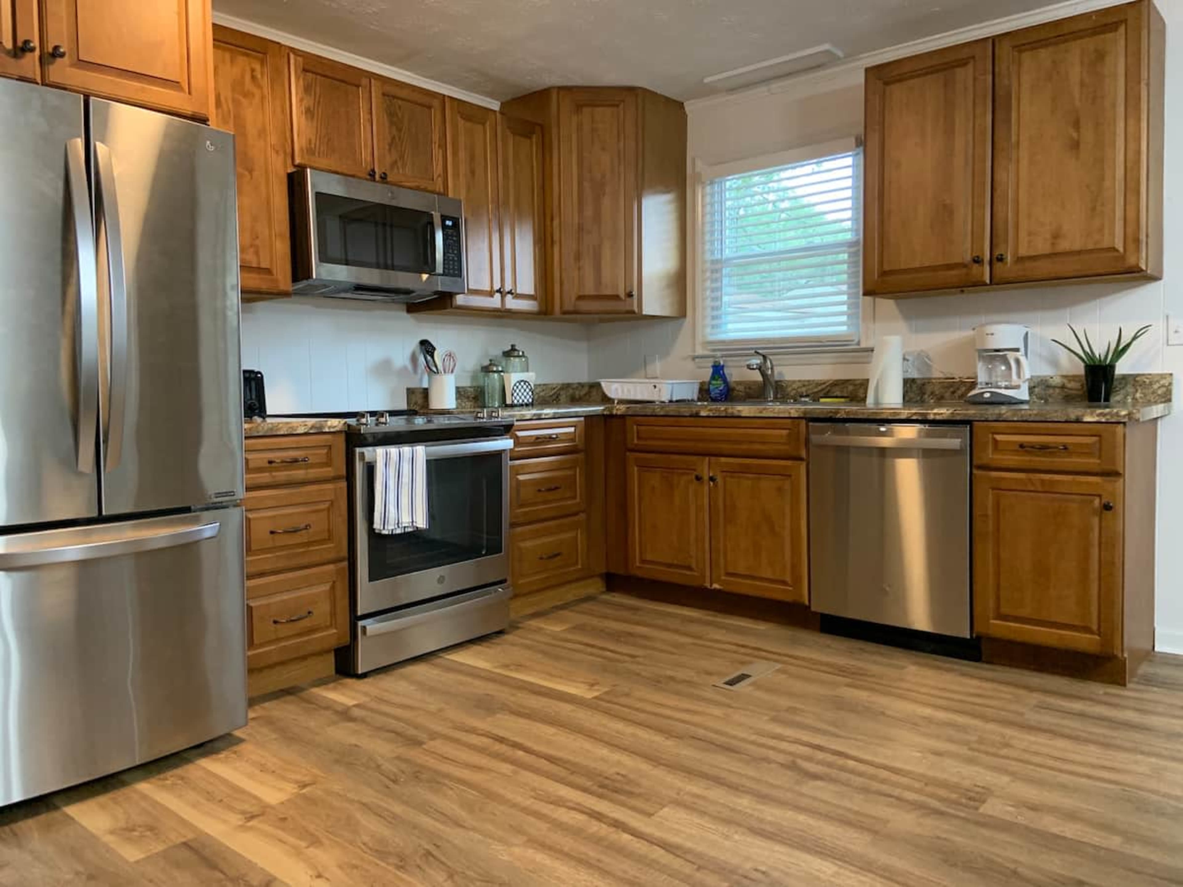 A kitchen with wooden cabinets, stainless steel appliances, and a light wood floor.
