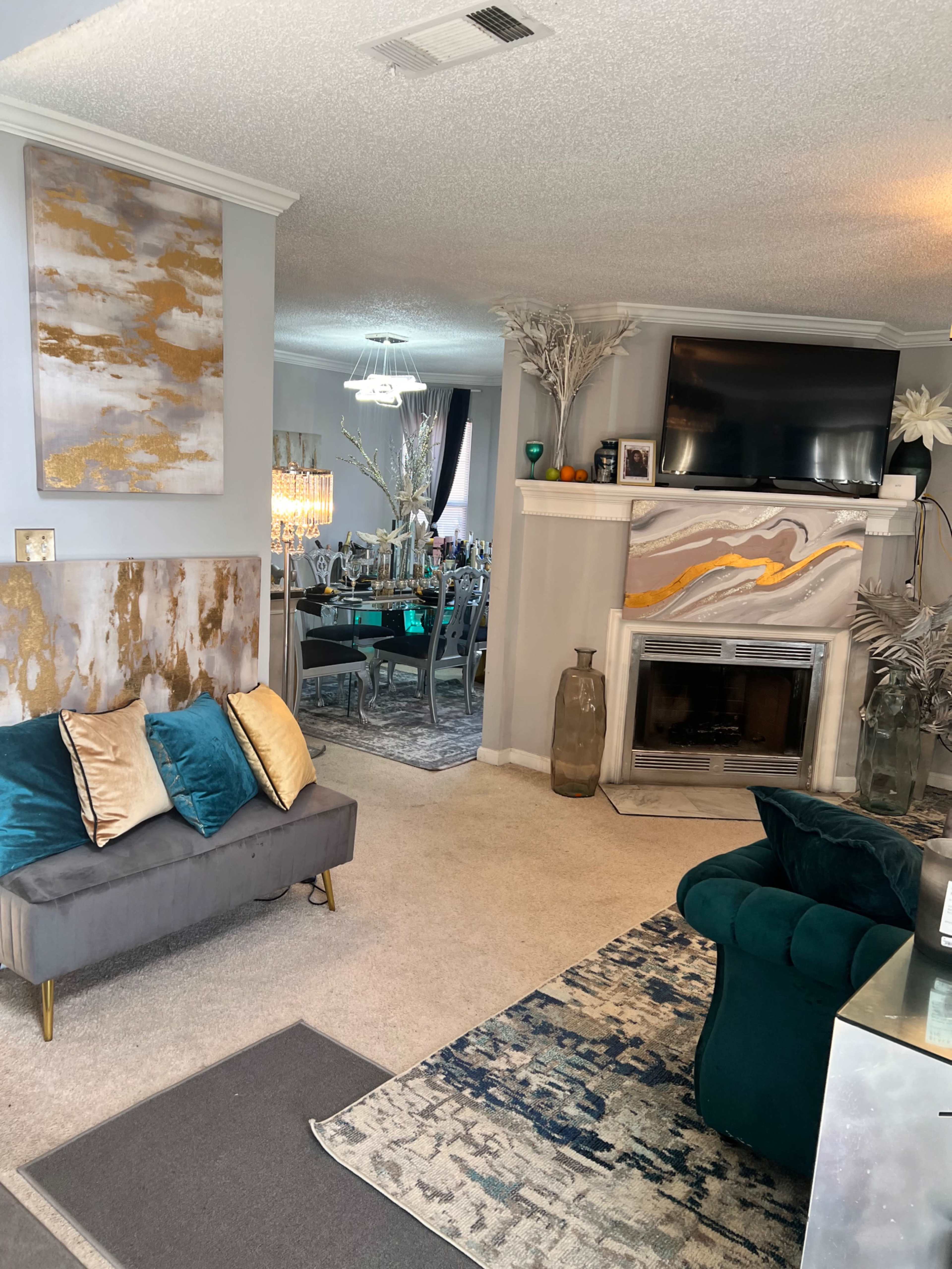 A living room with a gray sofa adorned with decorative pillows, a fireplace, and a dining area visible in the background.