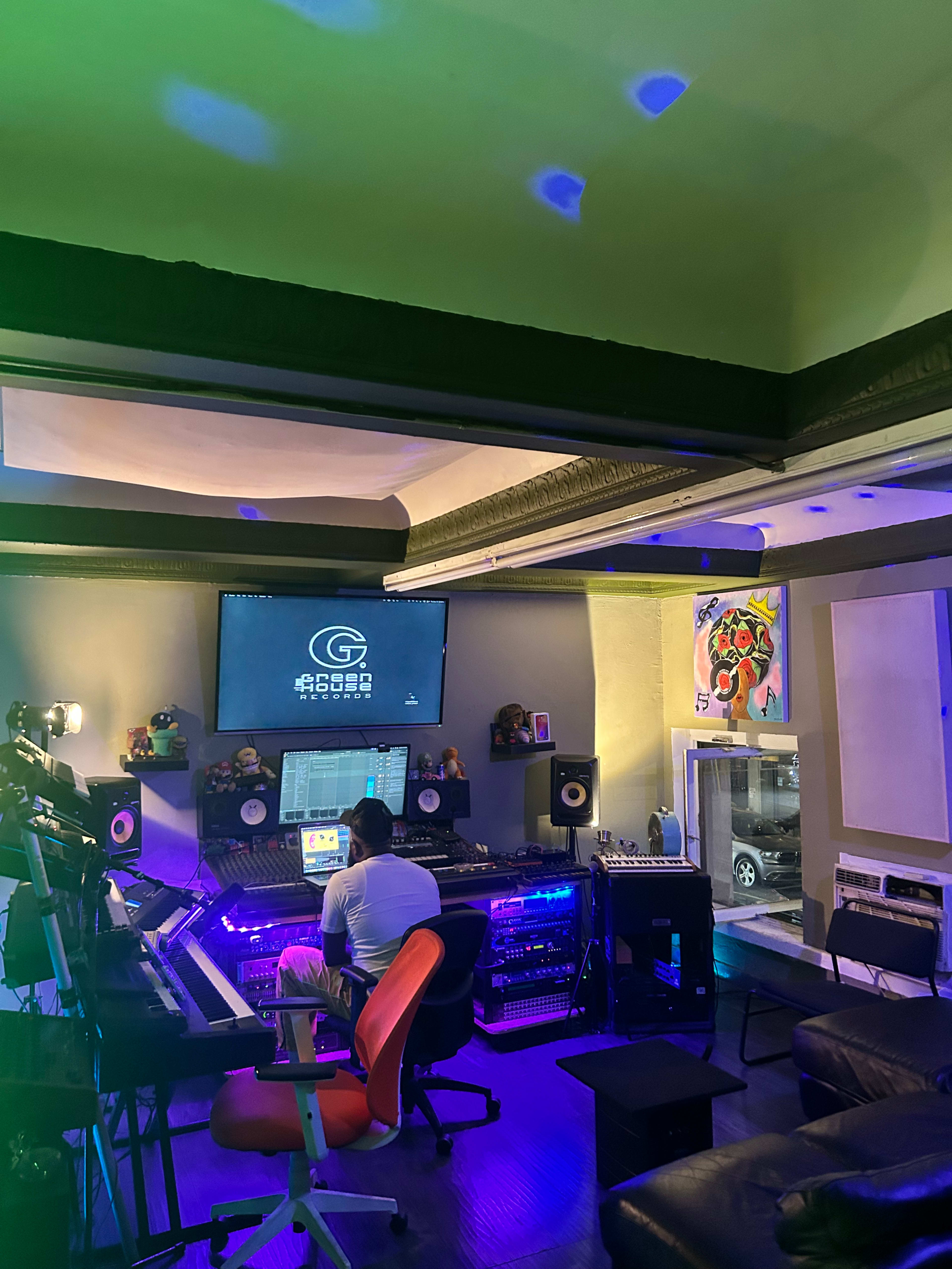 A person works at a music production studio equipped with various sound equipment and colorful lighting.
