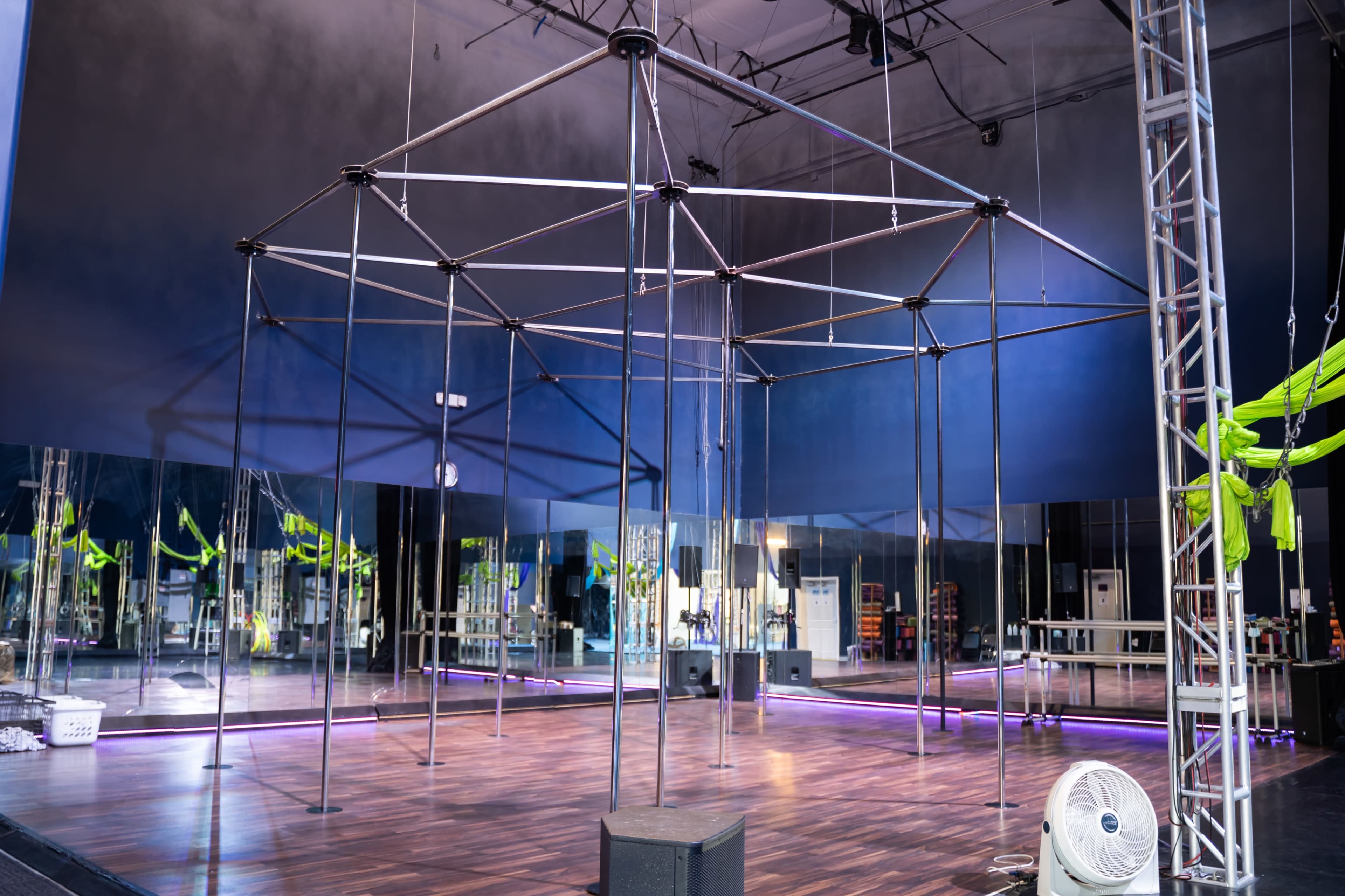 A large, metallic octagonal frame set up in an empty room with mirrors and a wooden floor.