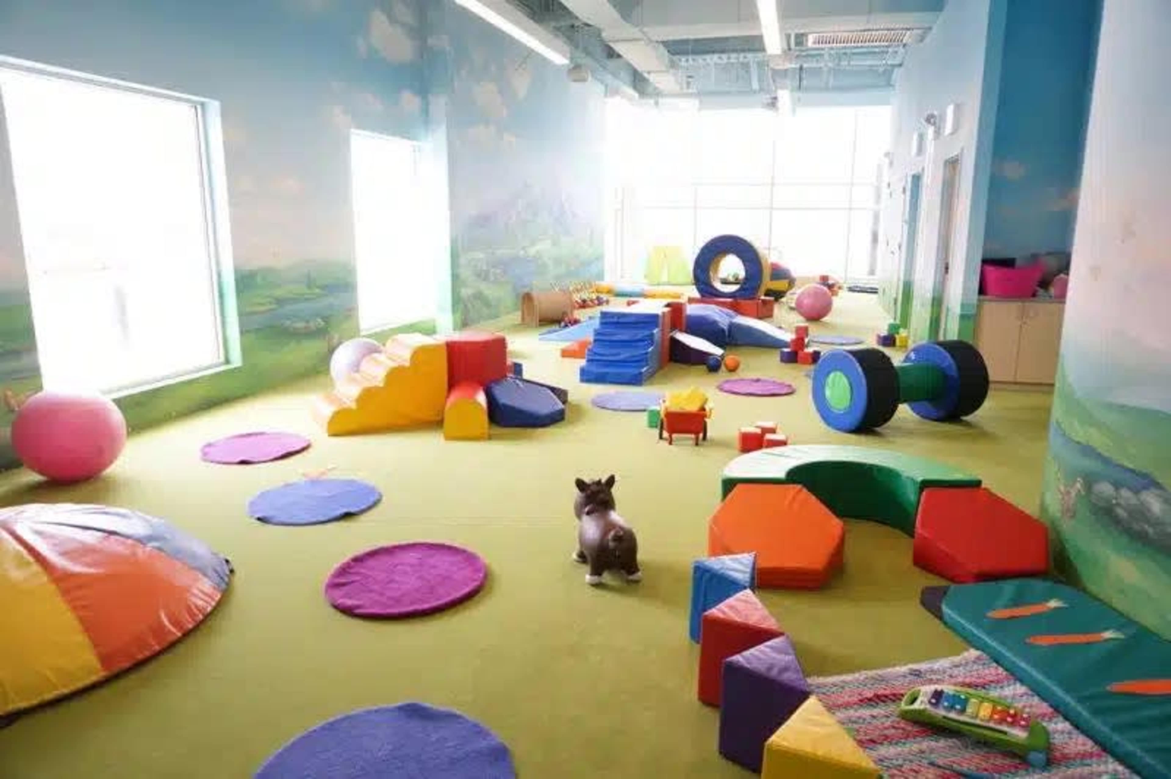 A colorful playroom filled with various geometric blocks, soft mats, and toys scattered across the floor.