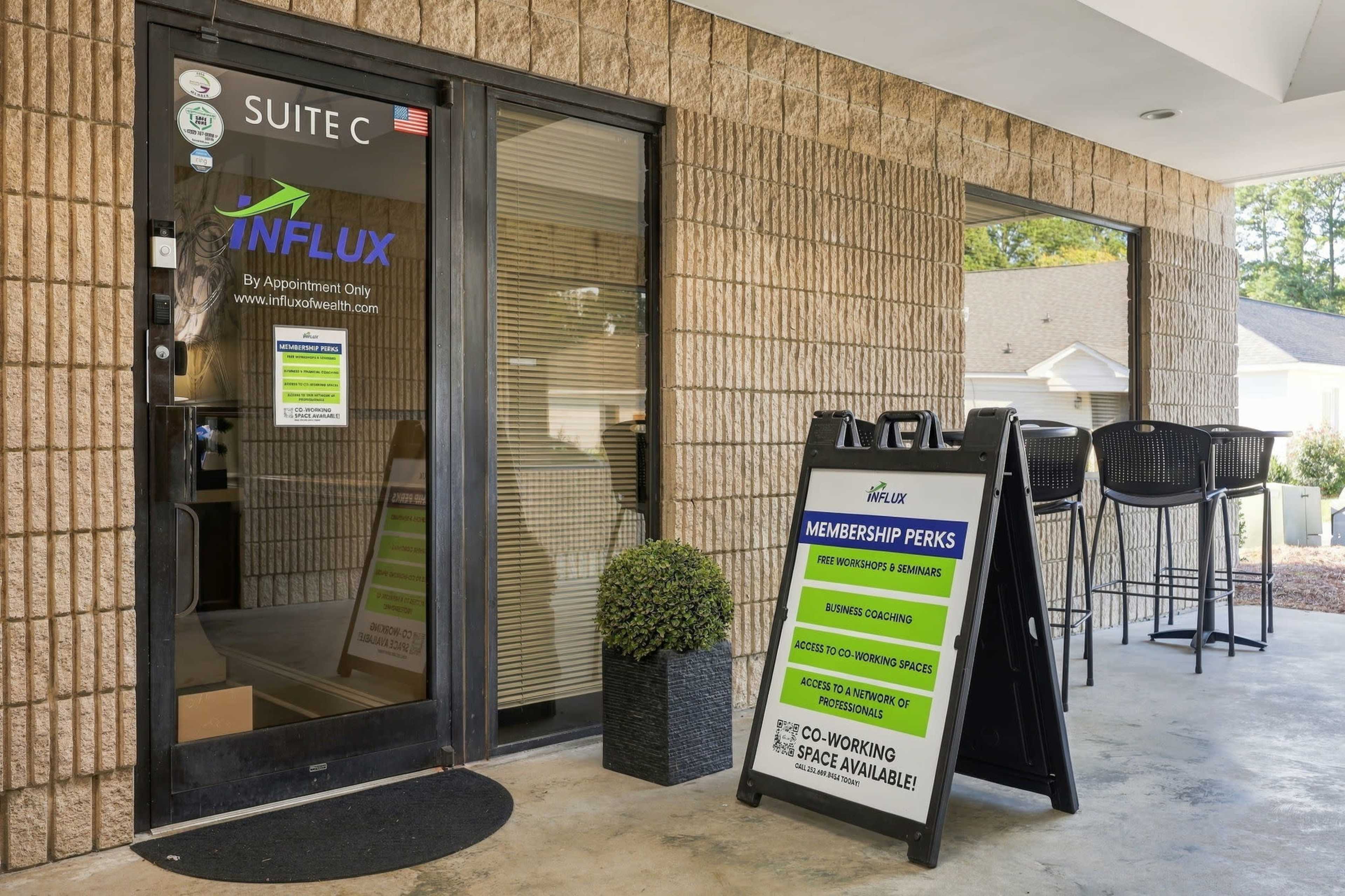 The image shows the entrance to a business named Influx, featuring a glass door with signage indicating membership perks and a black sandwich board displaying additional offerings outside.