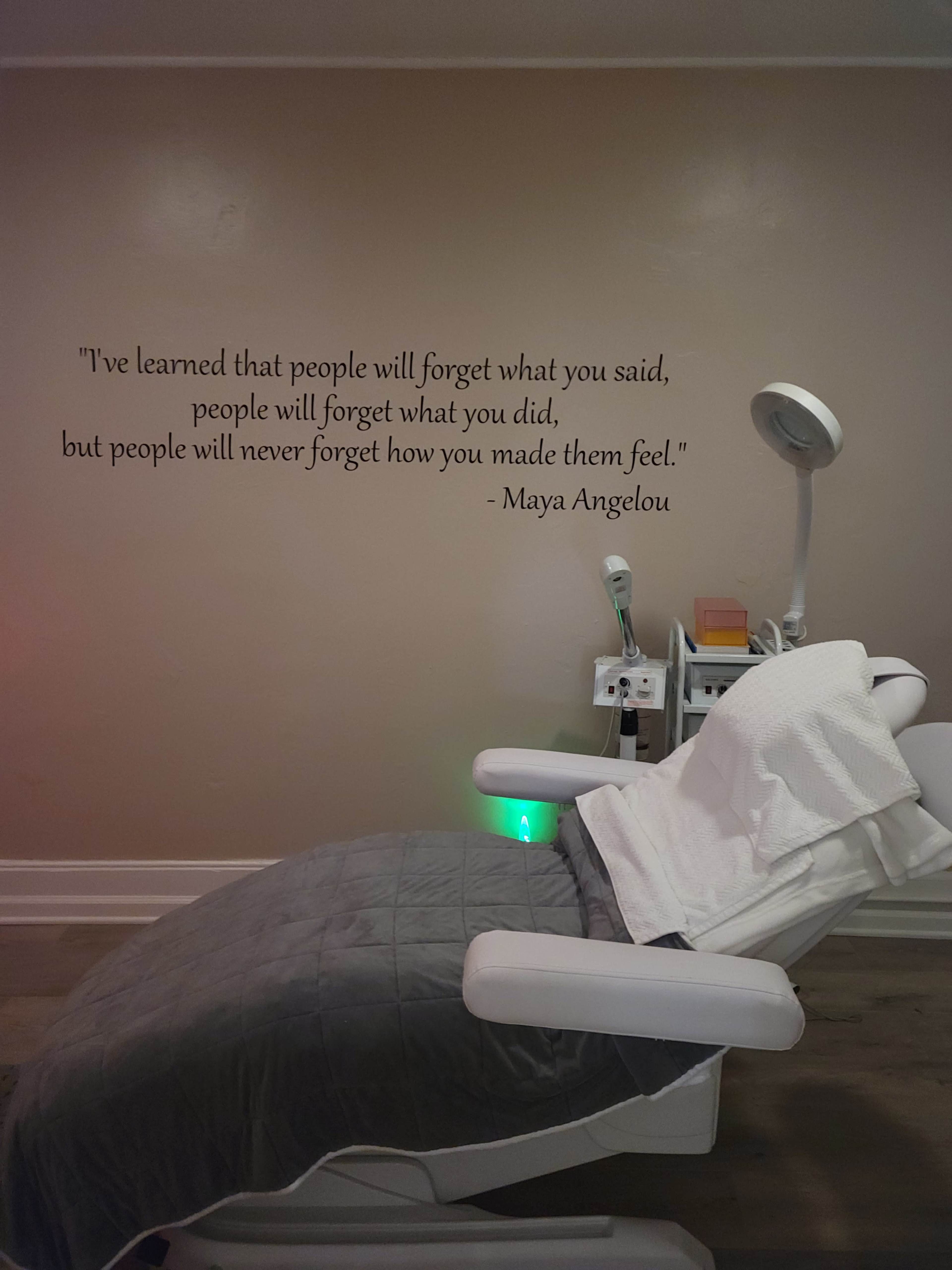 A treatment room with a reclining chair covered by a blanket, situated beneath a wall displaying a quote by Maya Angelou.