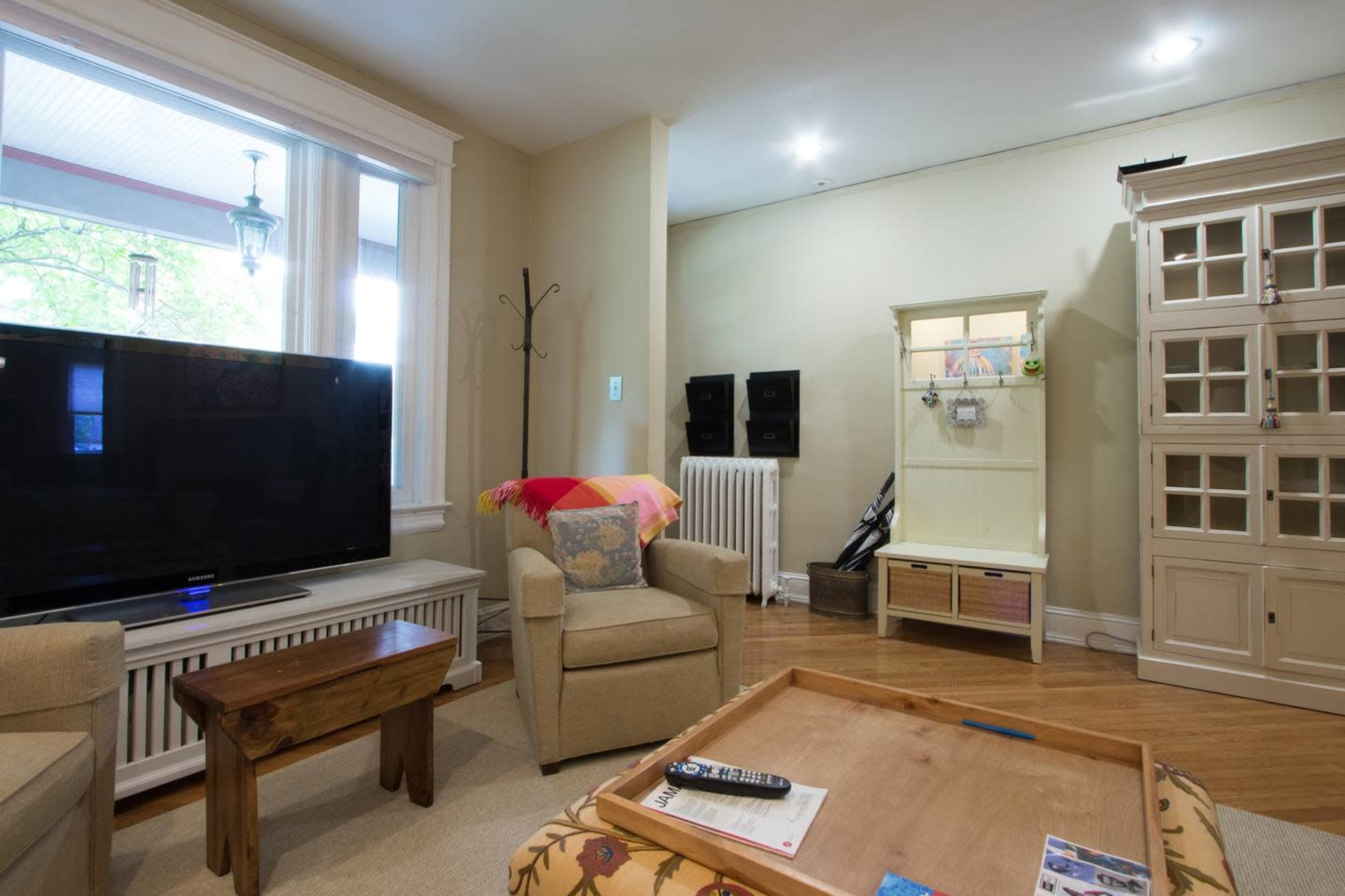 A living room with a television, a light-colored chair, a wooden coffee table, and a cabinet against the wall.