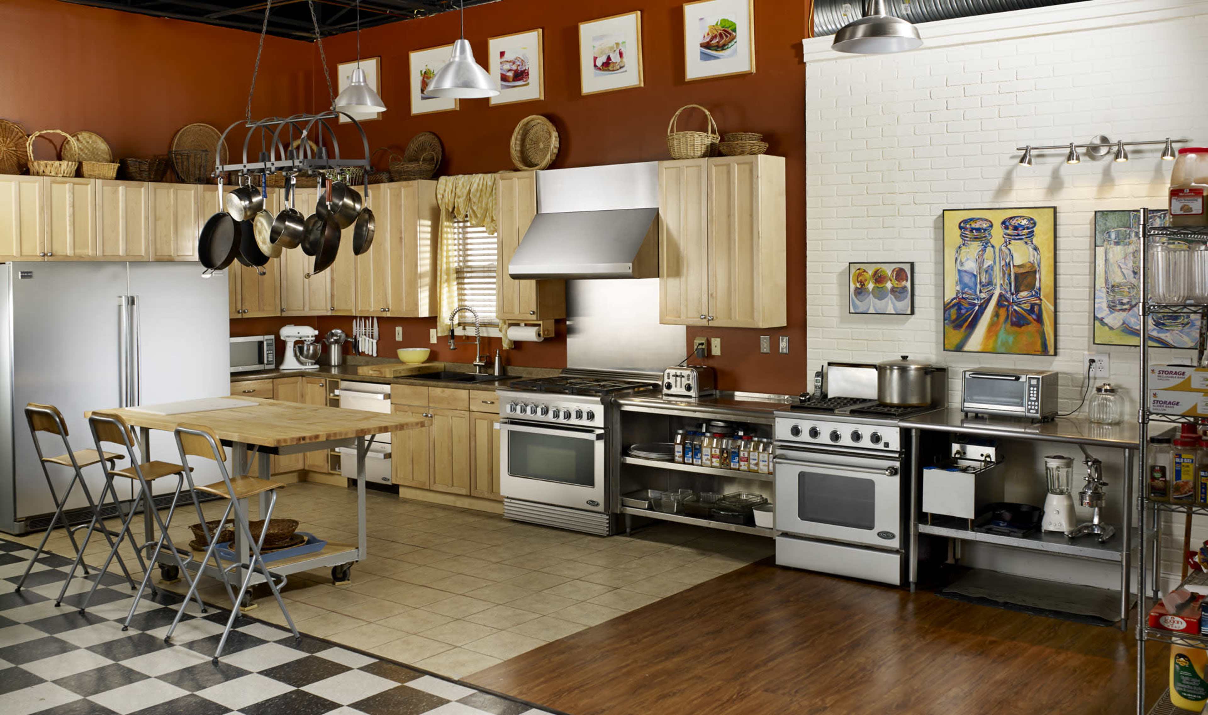 A modern kitchen features wooden cabinets, stainless steel appliances, and a large island with seating, arranged in a functional layout.