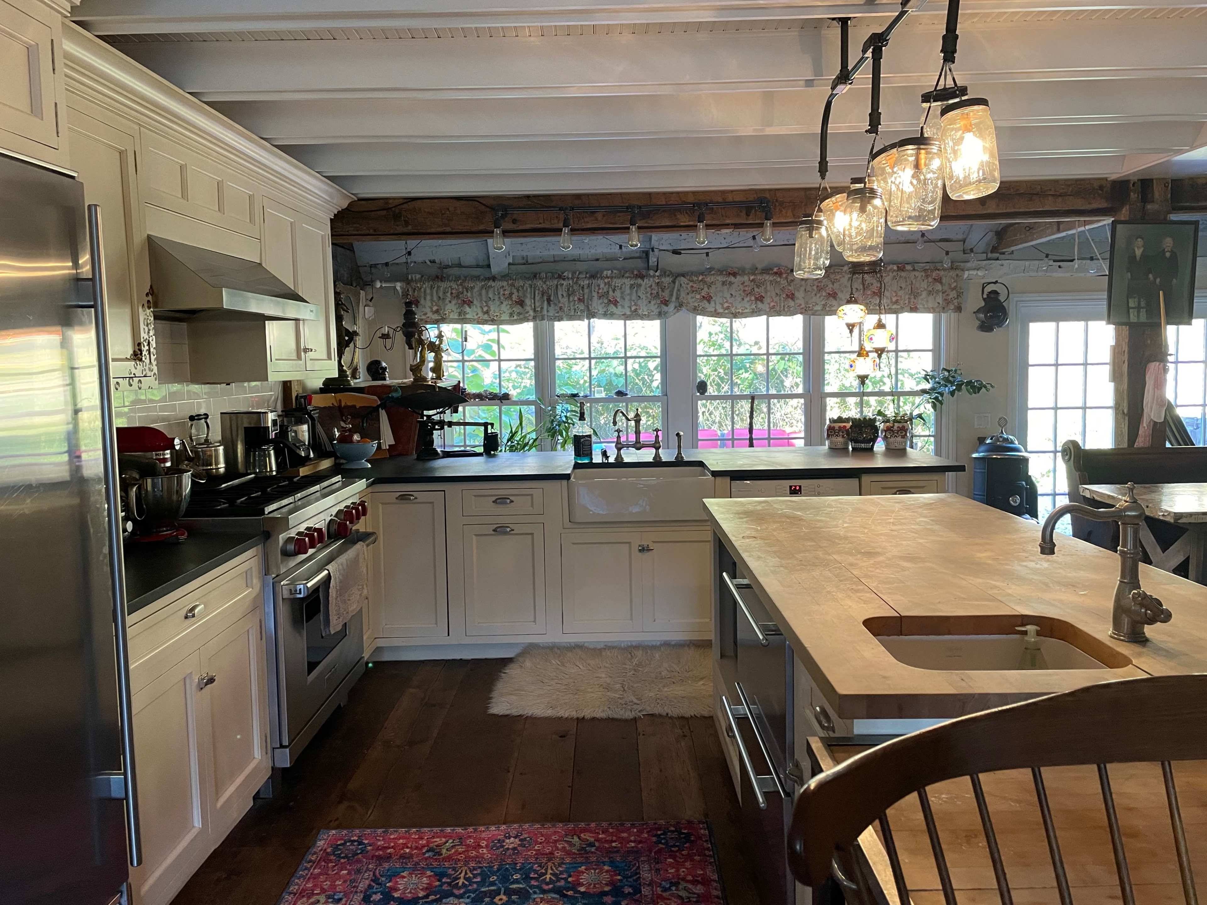 A well-organized kitchen featuring white cabinetry, stainless steel appliances, and a central wooden island with a sink.