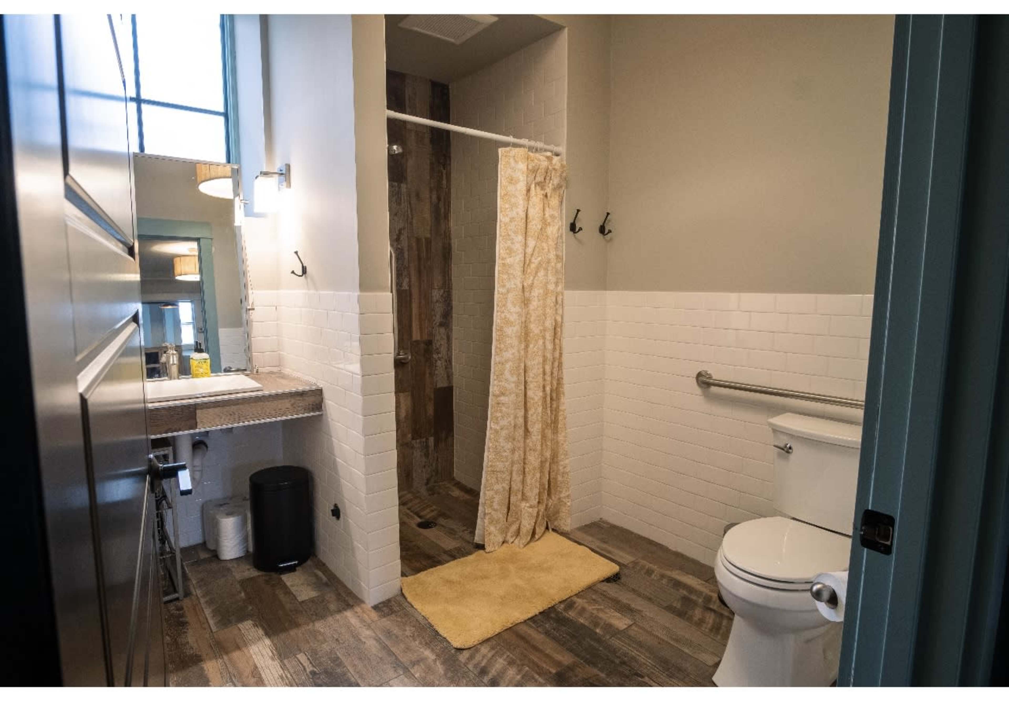 A bathroom featuring a shower area with a curtain, a toilet, a sink with a countertop, and tiled flooring.