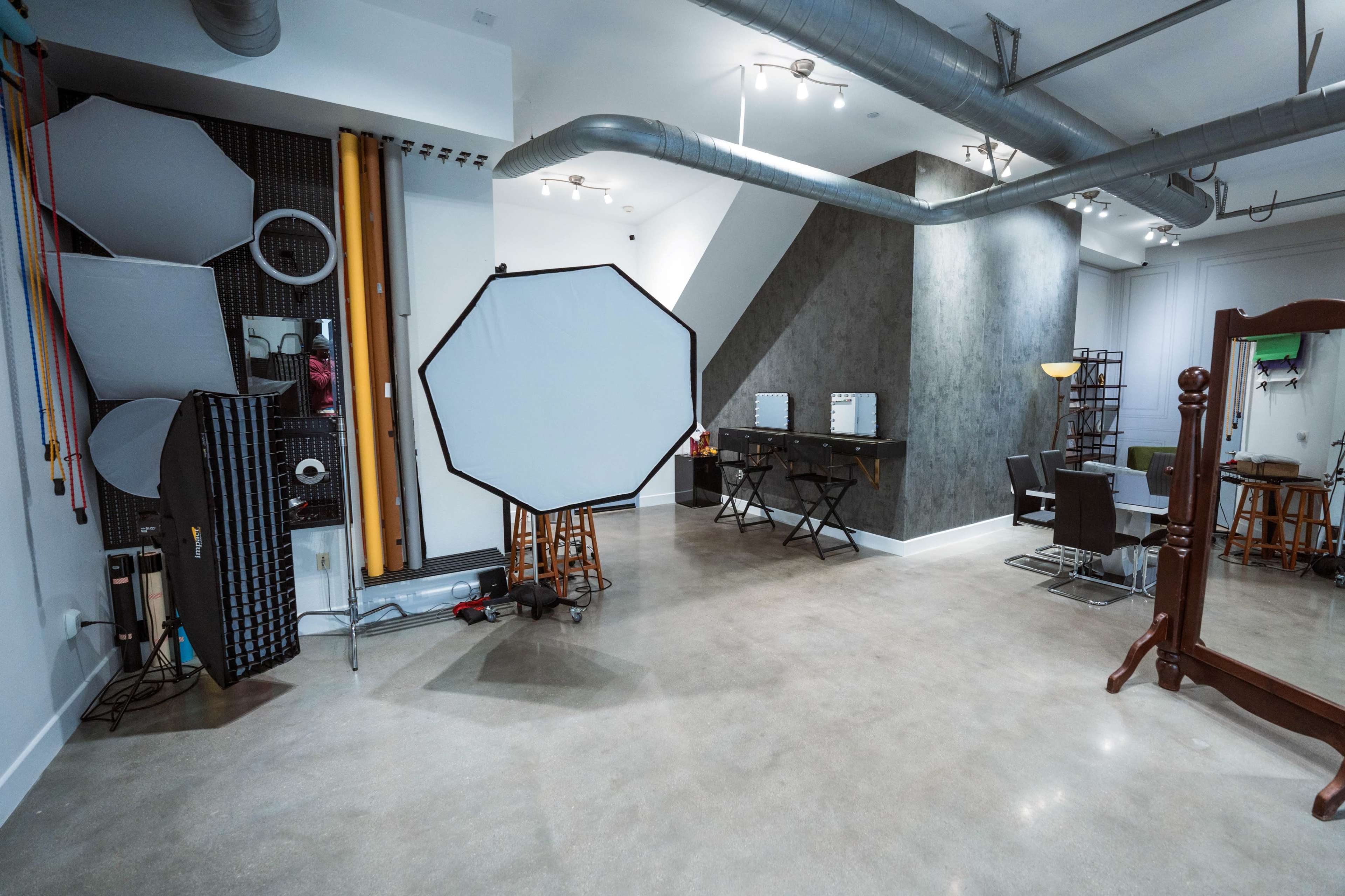 A photography studio featuring lighting equipment, a mirror area, and multiple workstations arranged in an open layout with industrial elements.