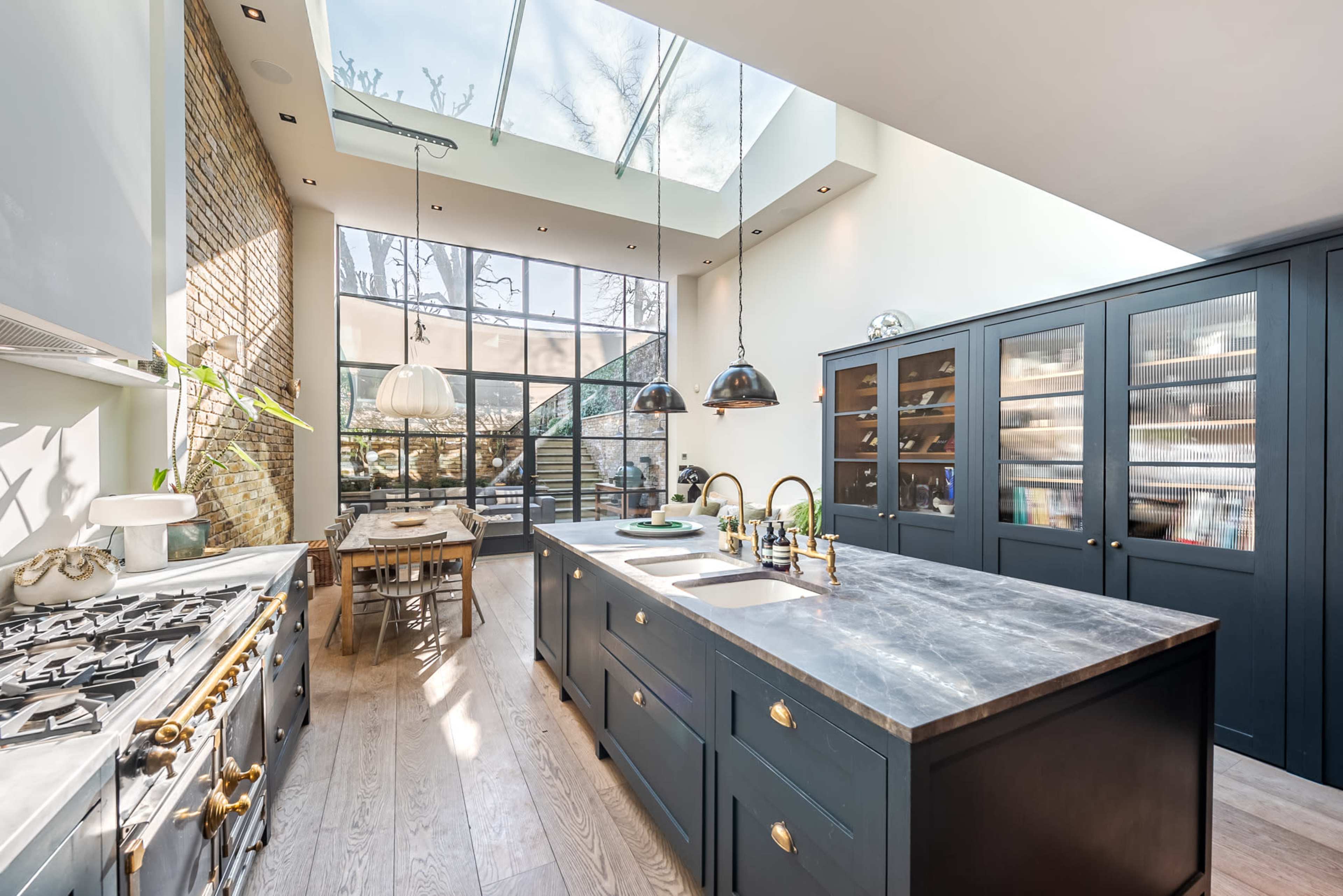 The kitchen features a large central island with a gray marble countertop, dark cabinetry, and expansive windows that provide natural light.