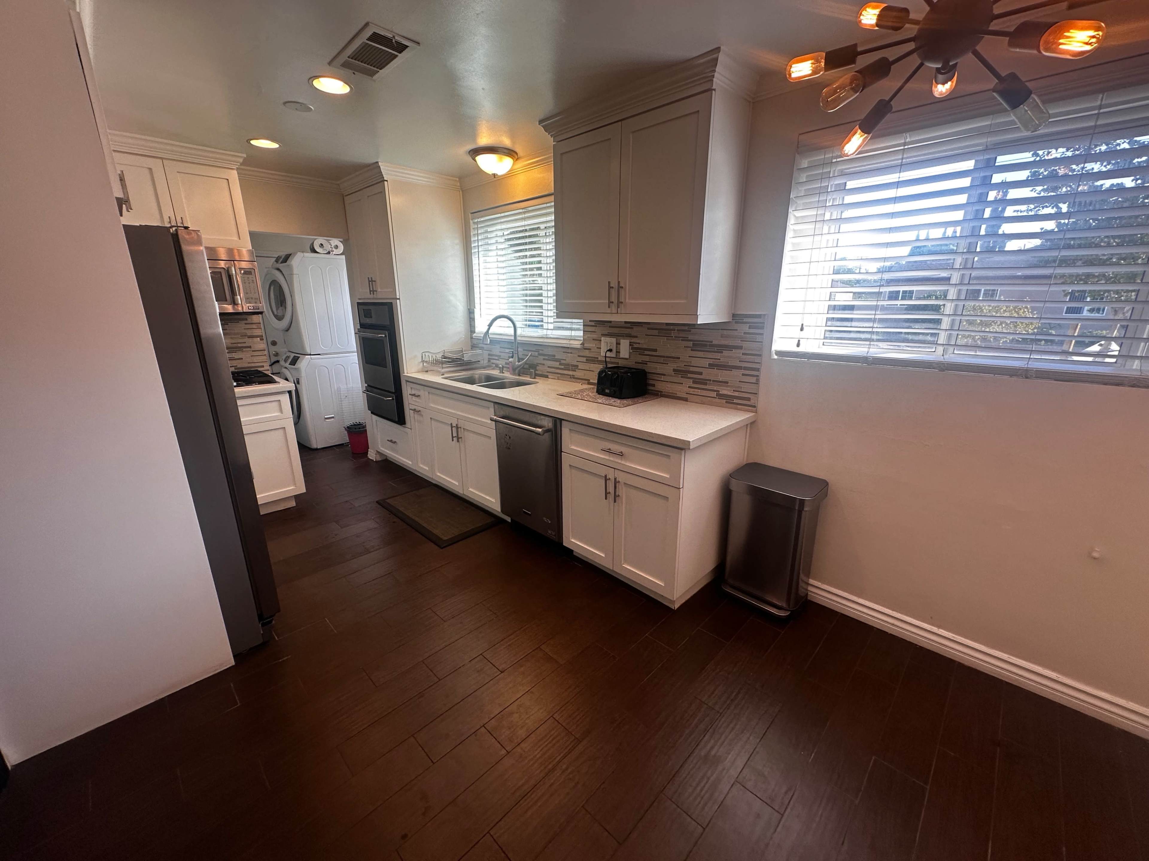 A modern kitchen featuring white cabinetry, stainless steel appliances, and hardwood flooring.