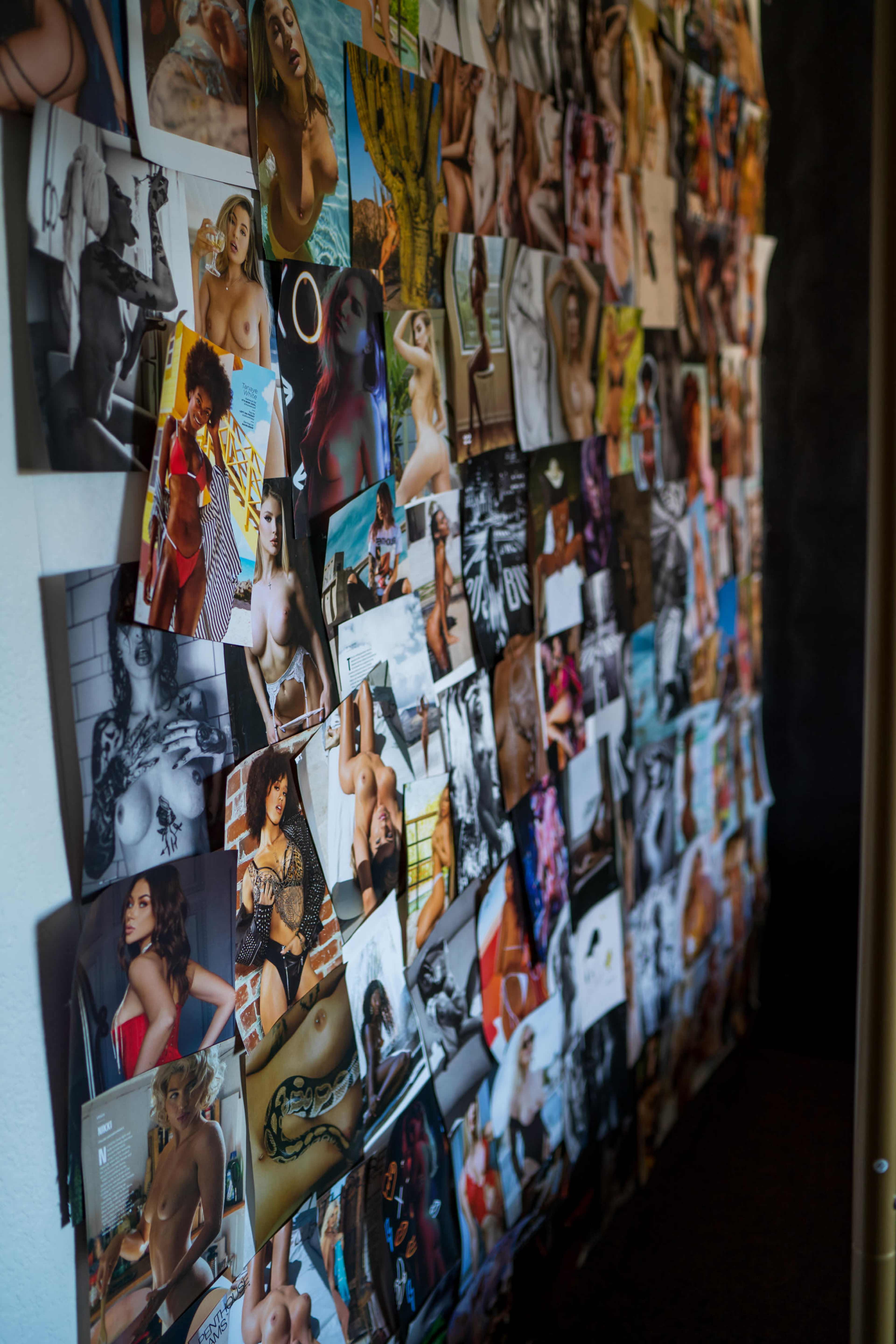 A wall is covered with a collage of various photographs featuring people in artistic poses and expressions.