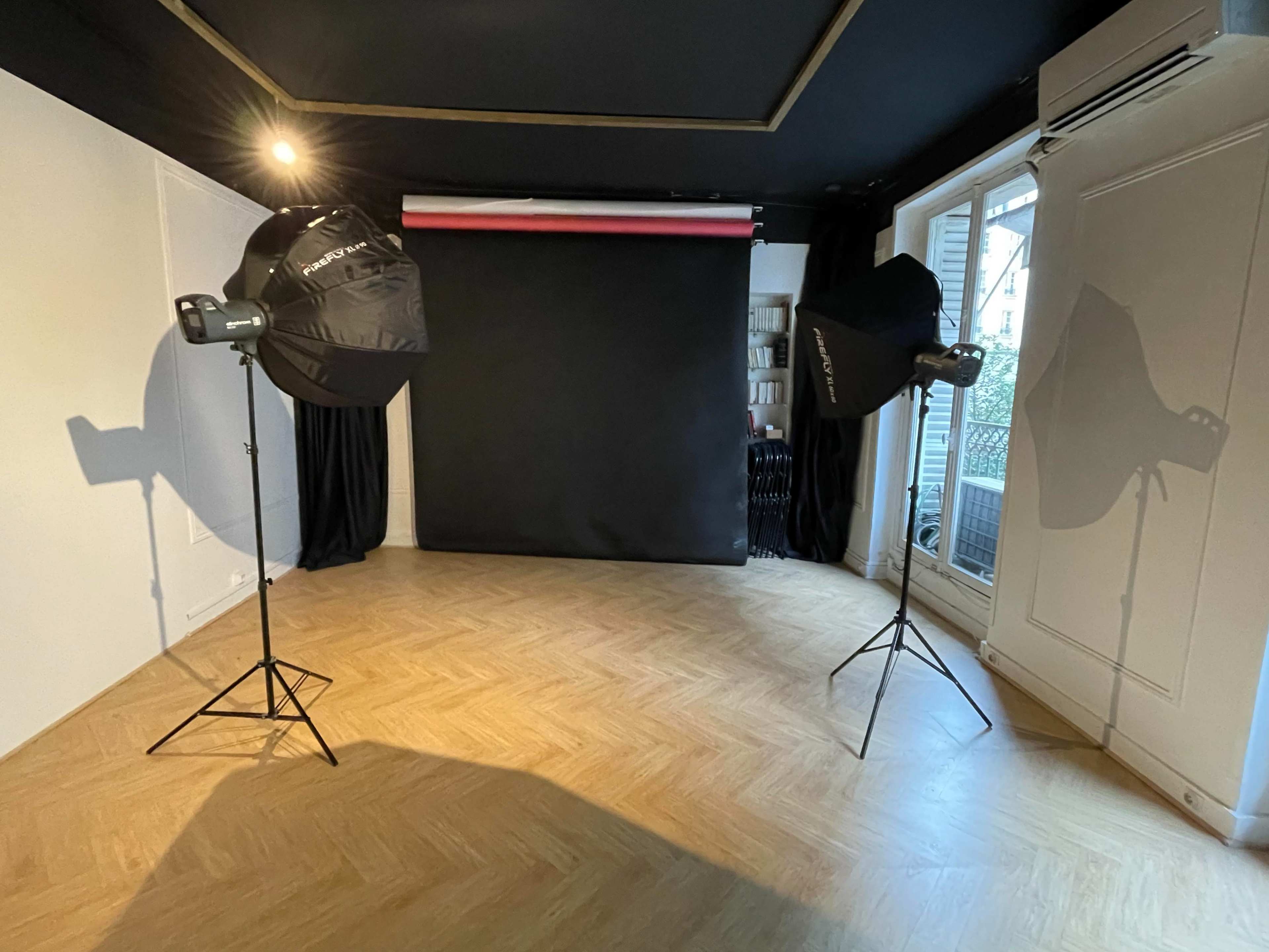 A photography studio equipped with two light stands and a black backdrop.
