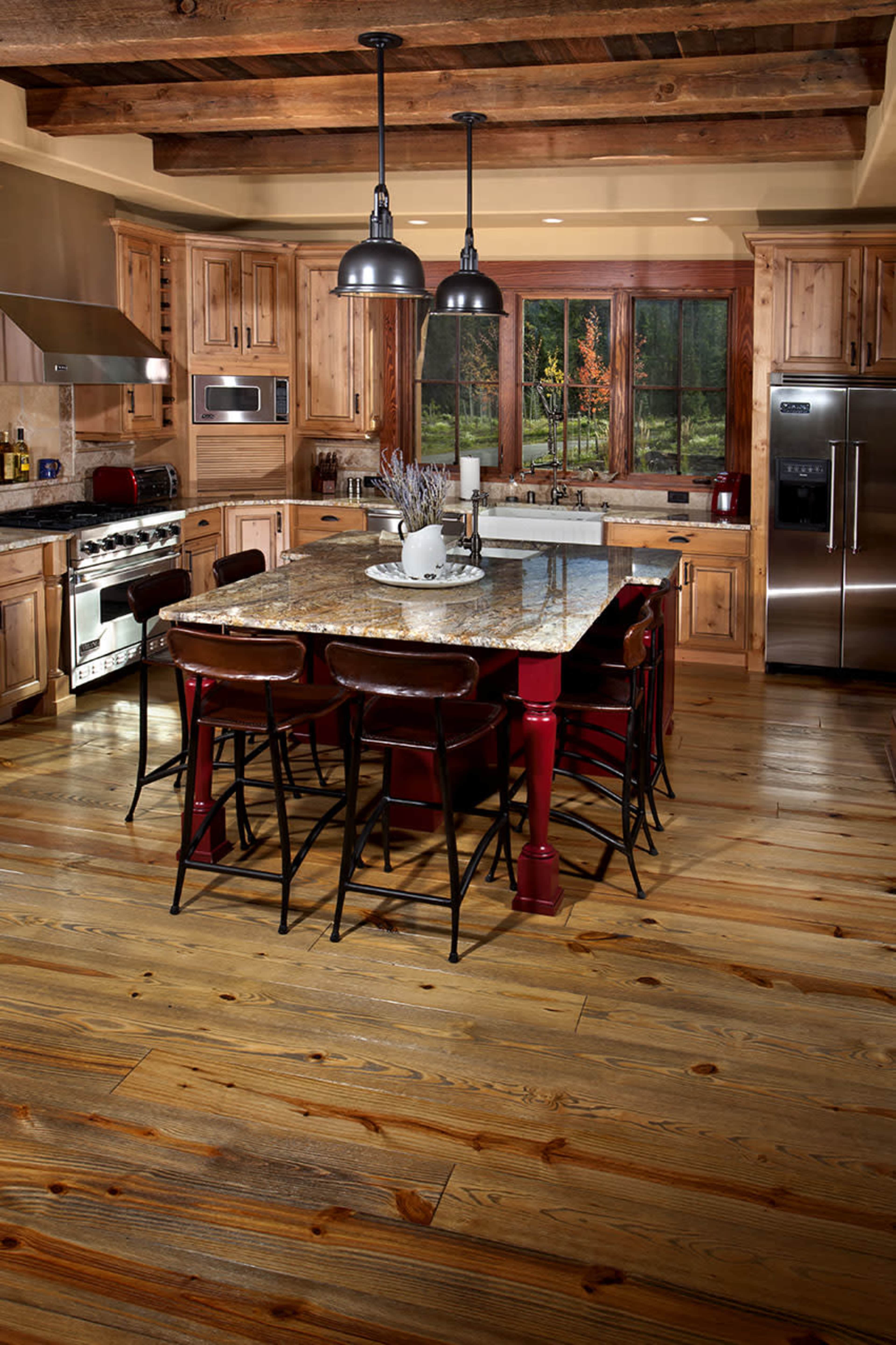 A spacious kitchen features a large granite island surrounded by barstools, wooden cabinets, and stainless steel appliances.