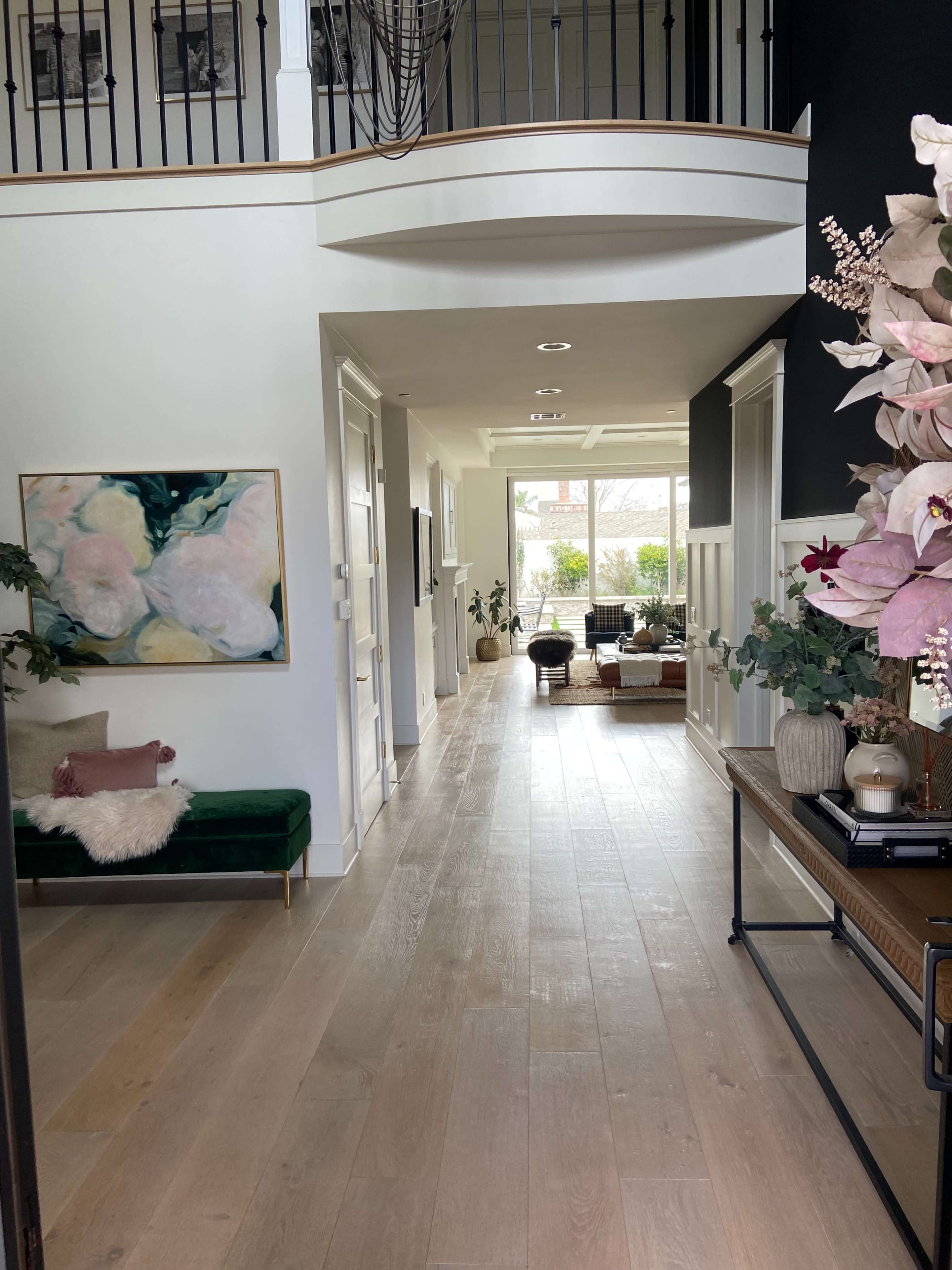 A spacious hallway leading to a living area, with a cozy seating arrangement and large windows allowing natural light.