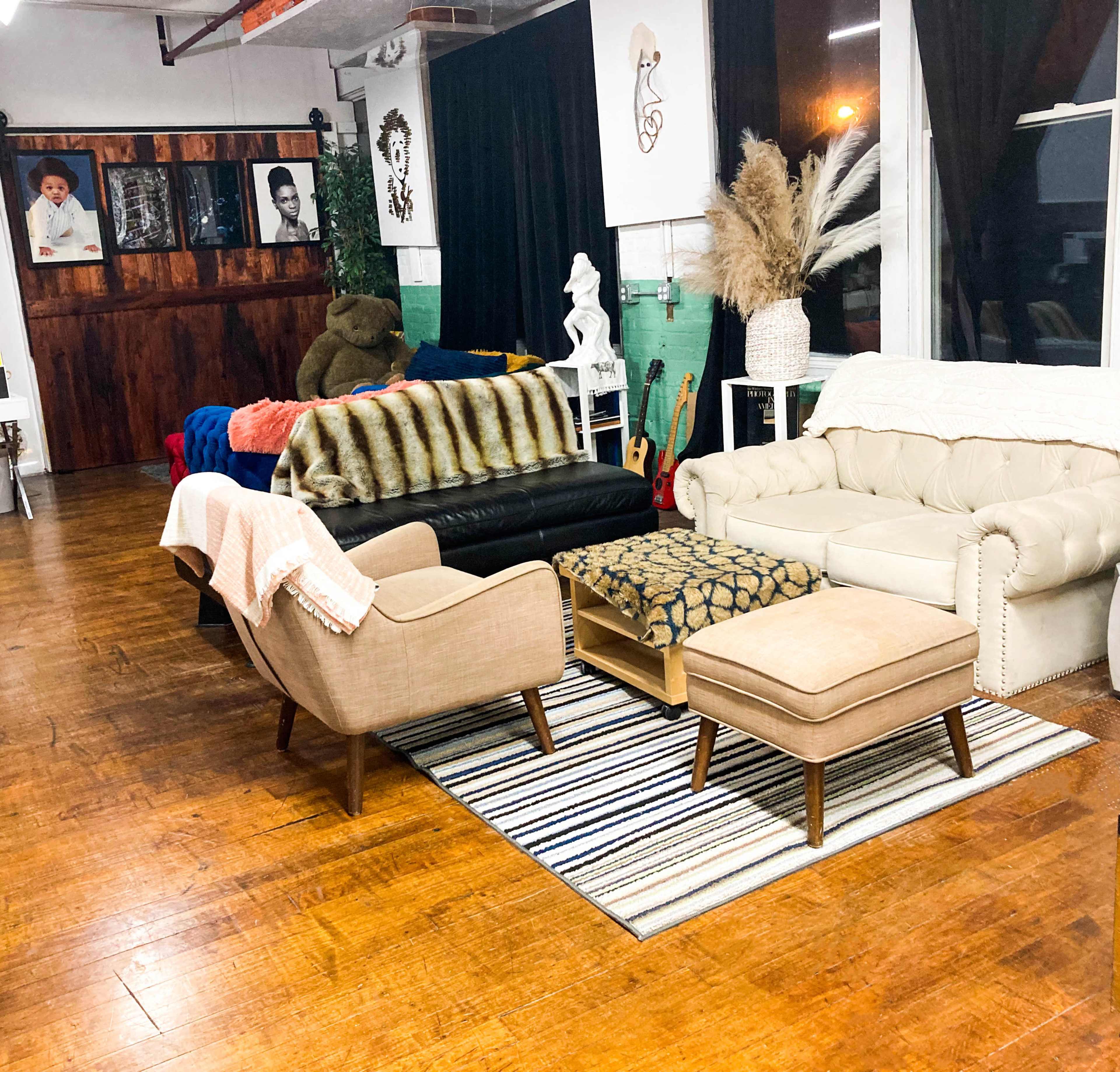 A cozy interior space featuring various seating arrangements, decorative textiles, and a few pieces of wall art.