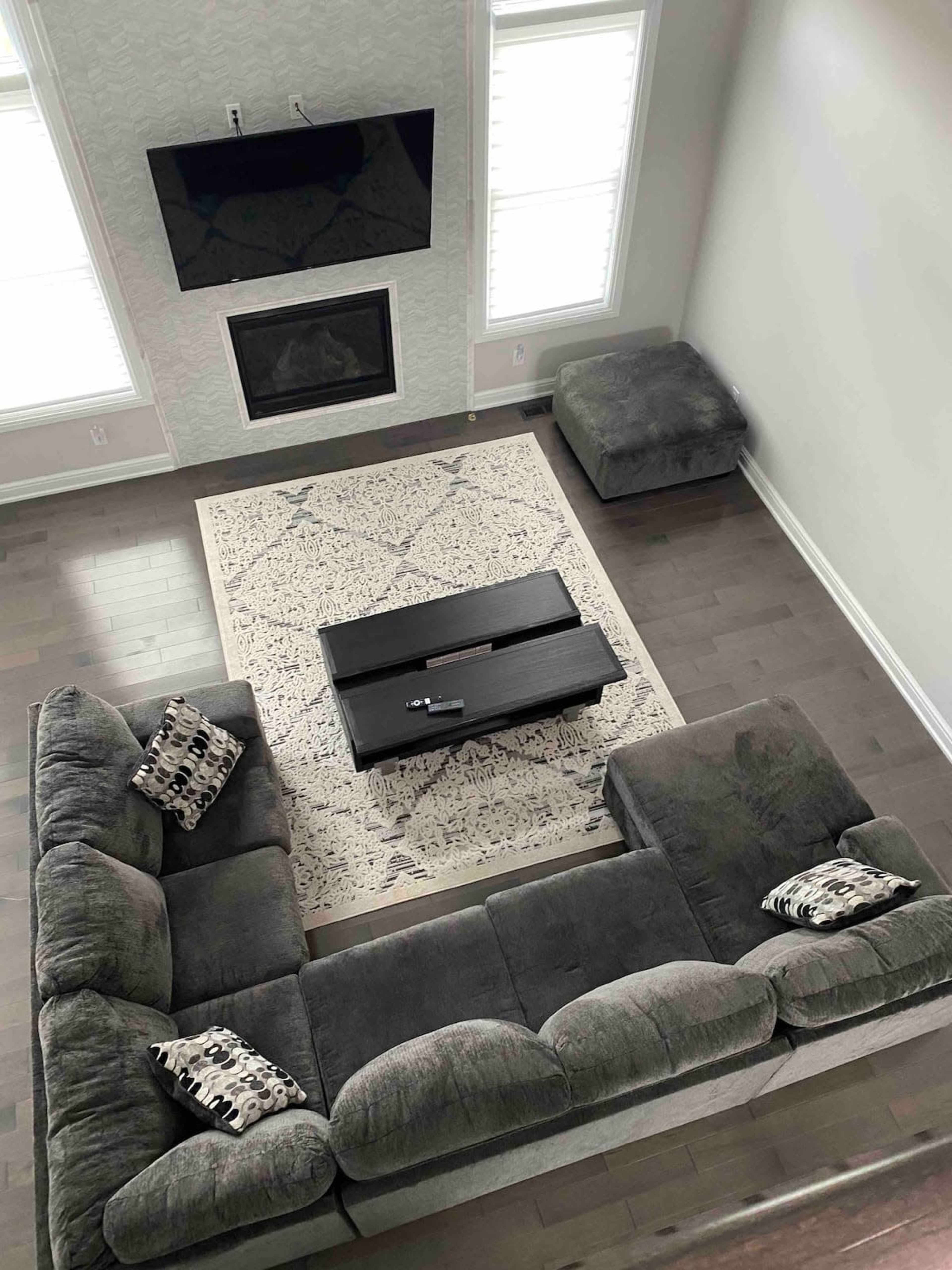 A modern living room with a sectional couch, a coffee table, and a television mounted on the wall.