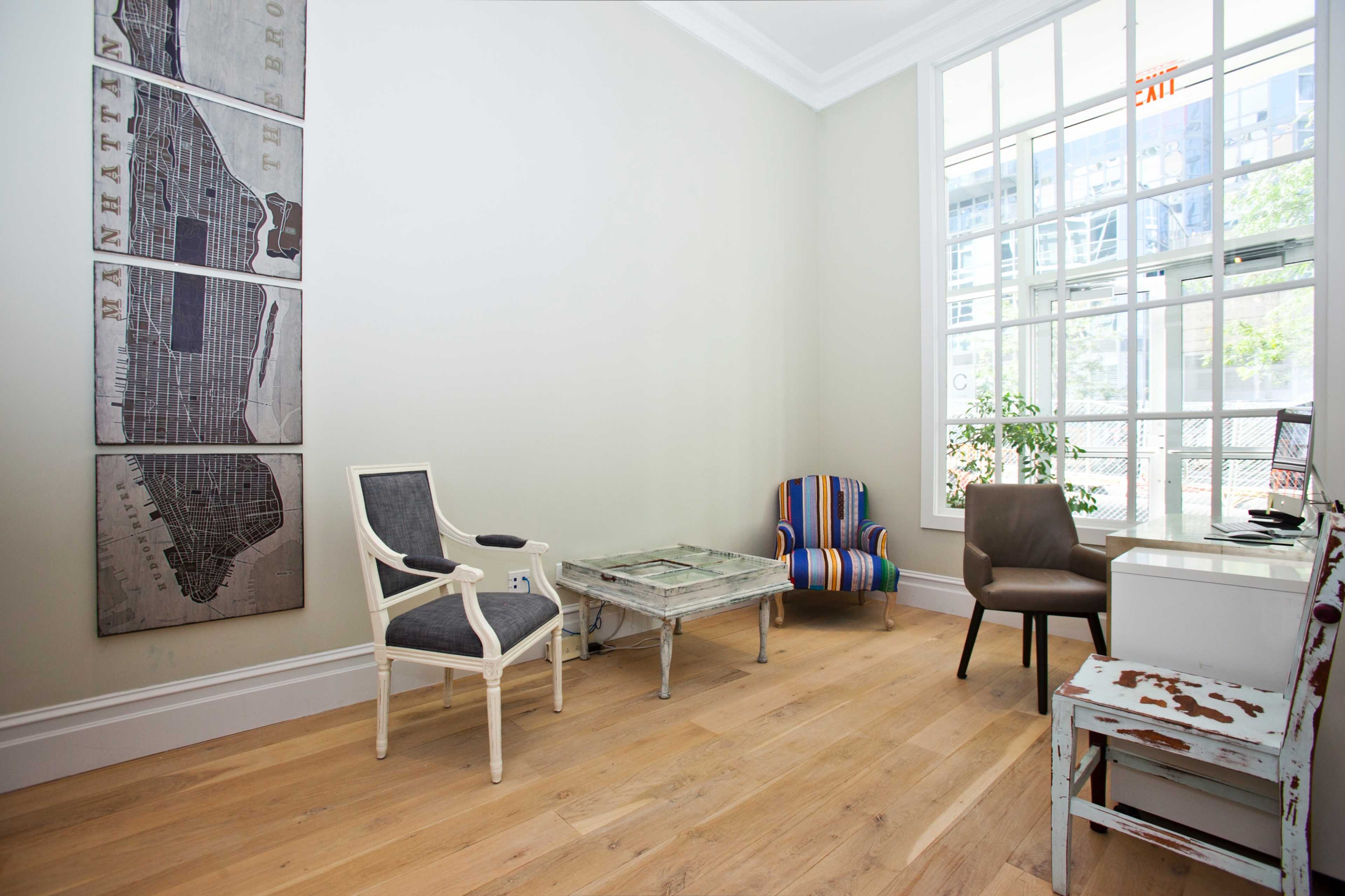 A modern waiting area with a variety of seating options, including a striped chair, a gray chair, and a glass coffee table, alongside a map decor on the wall.