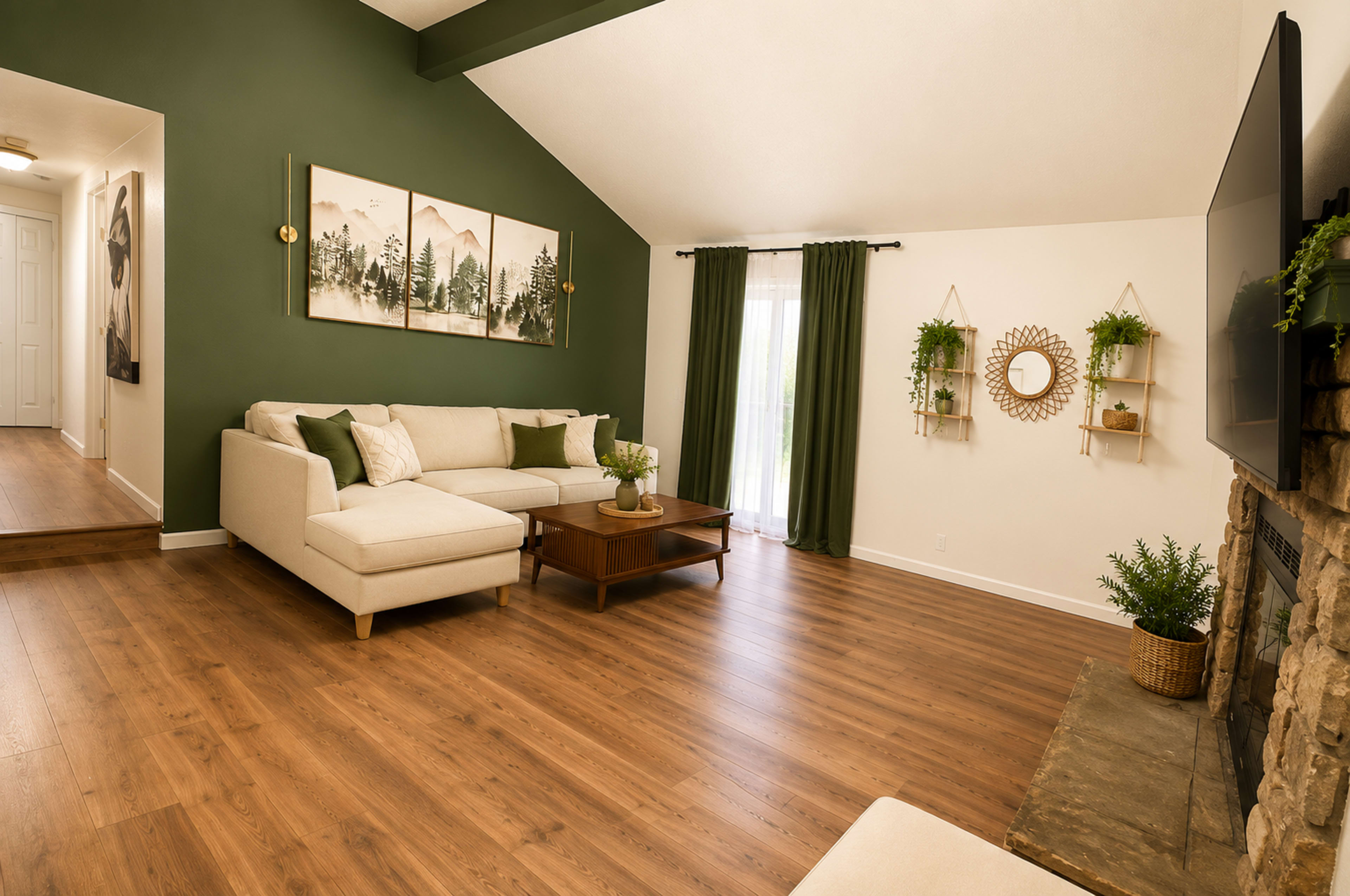 The living room features a light-colored sectional sofa, wooden flooring, and green accent walls, with decorative plants and artwork adorning the space.
