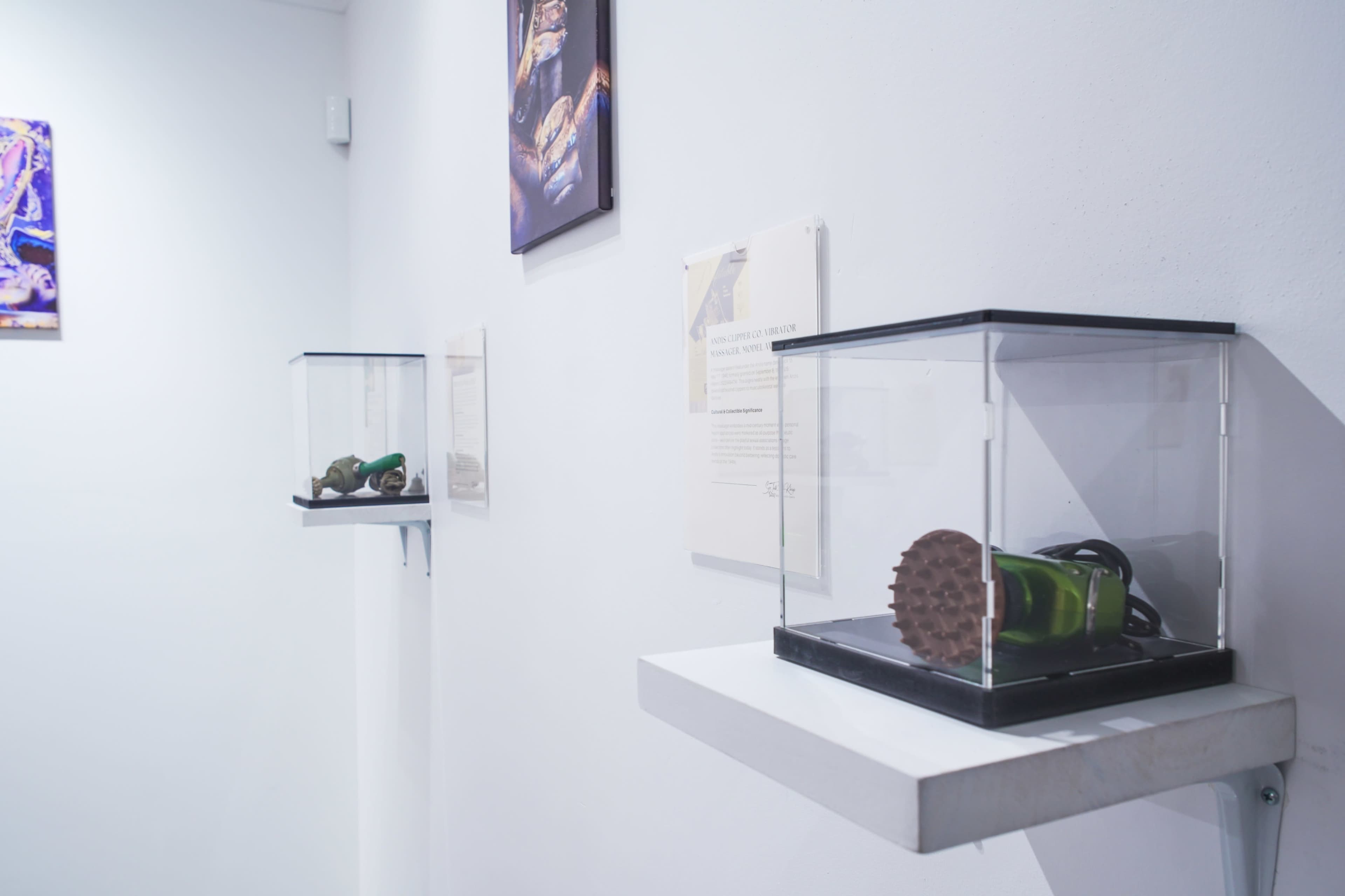 The image shows two glass display cases mounted on white walls, each containing an exhibit item with a brief description on the wall beside the cases.