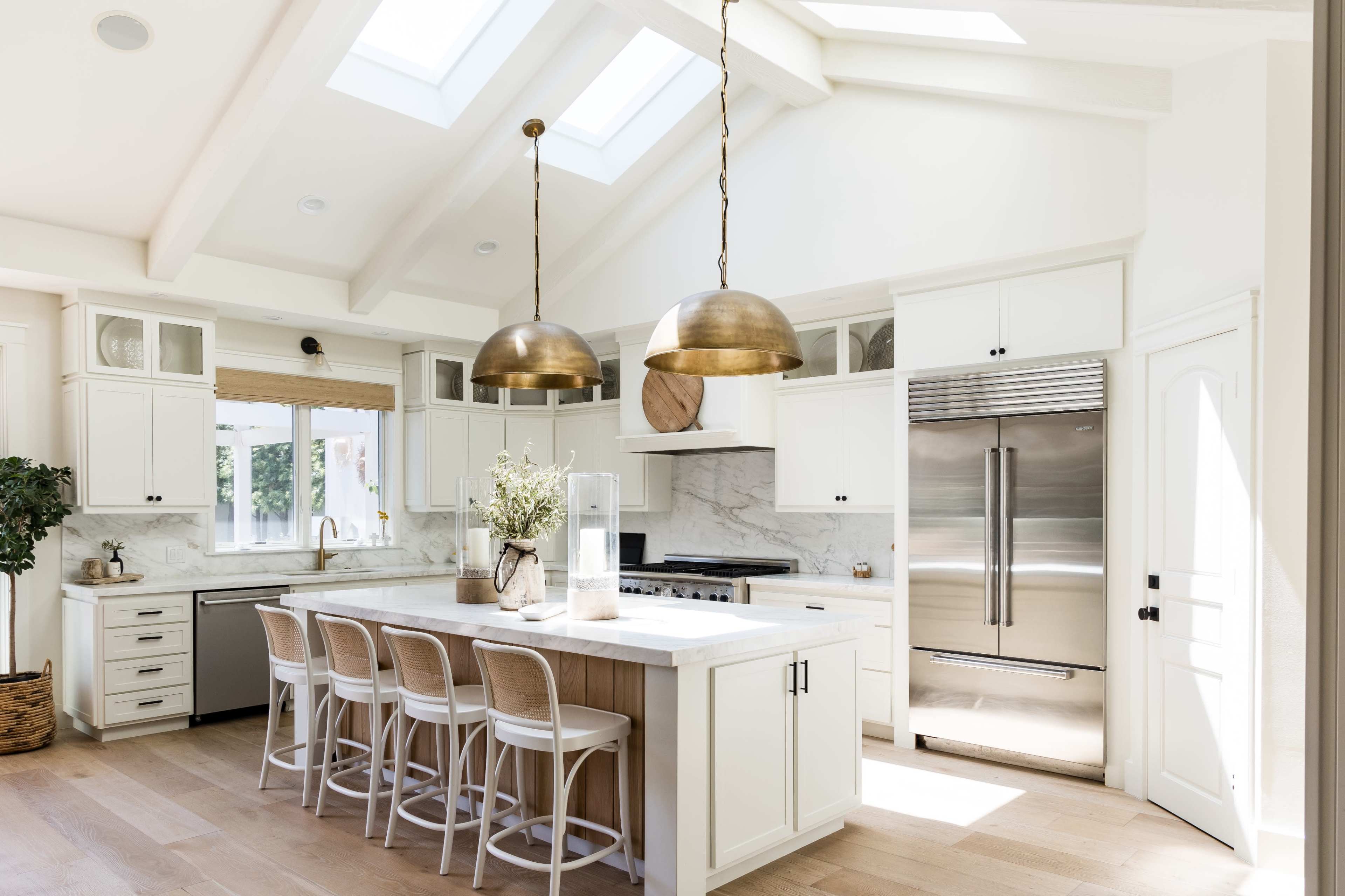 The kitchen features white cabinetry, a large island with seating, and skylights illuminating the space.
