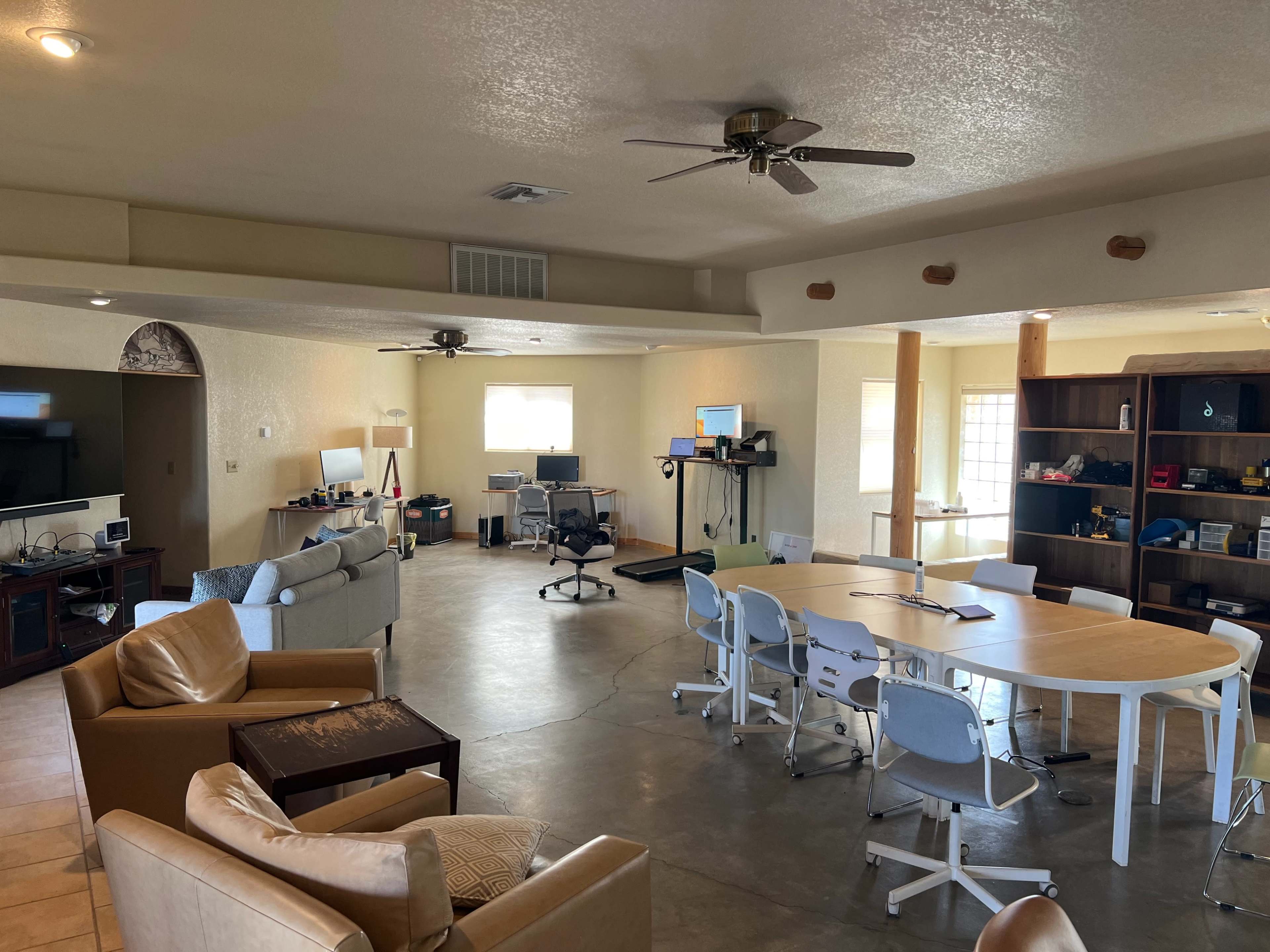 A spacious room with a combination of seating areas, workstations, and a conference table surrounded by chairs.