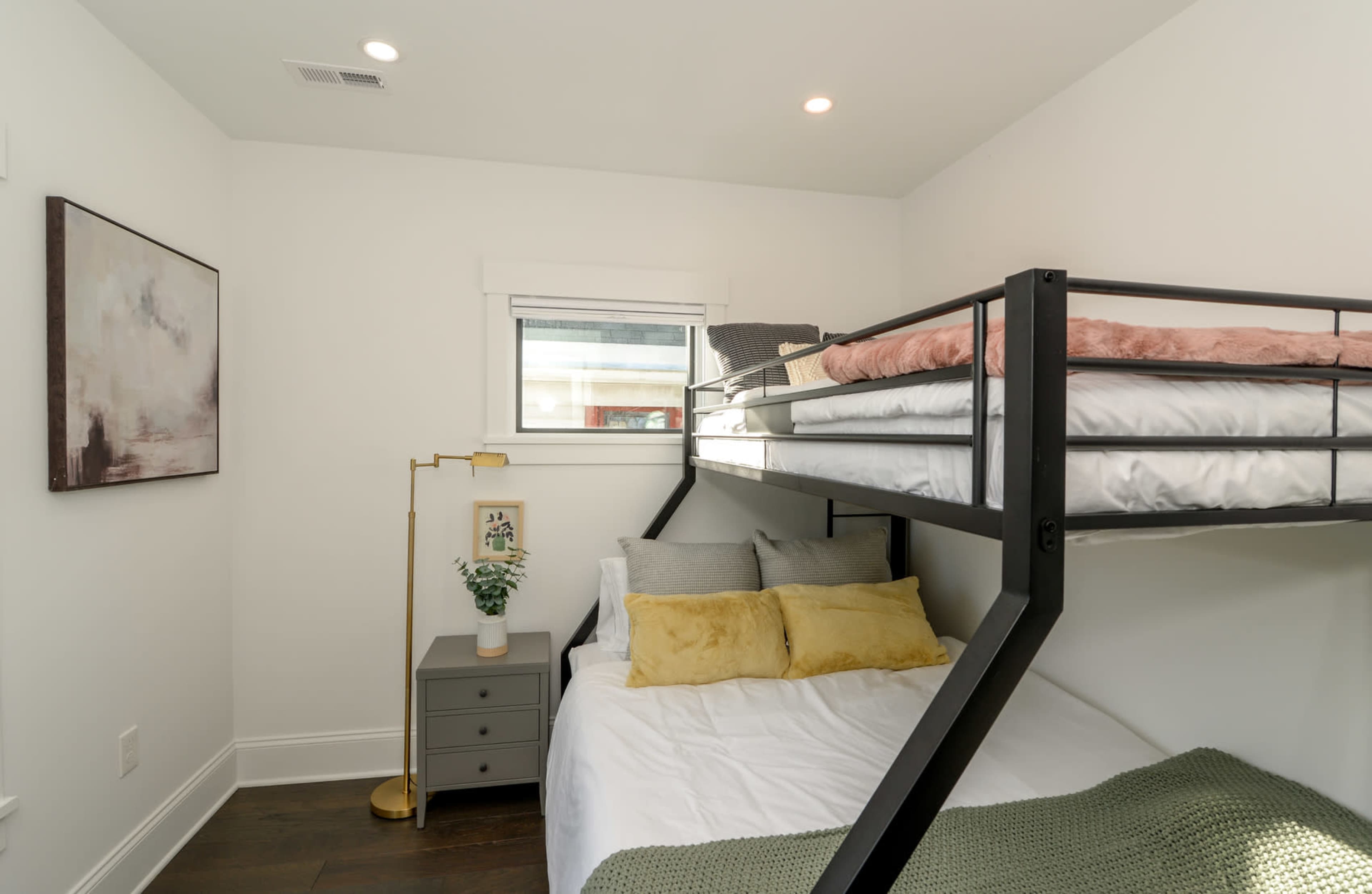 A small bedroom featuring a bunk bed, a bedside table, and a wall-mounted artwork.