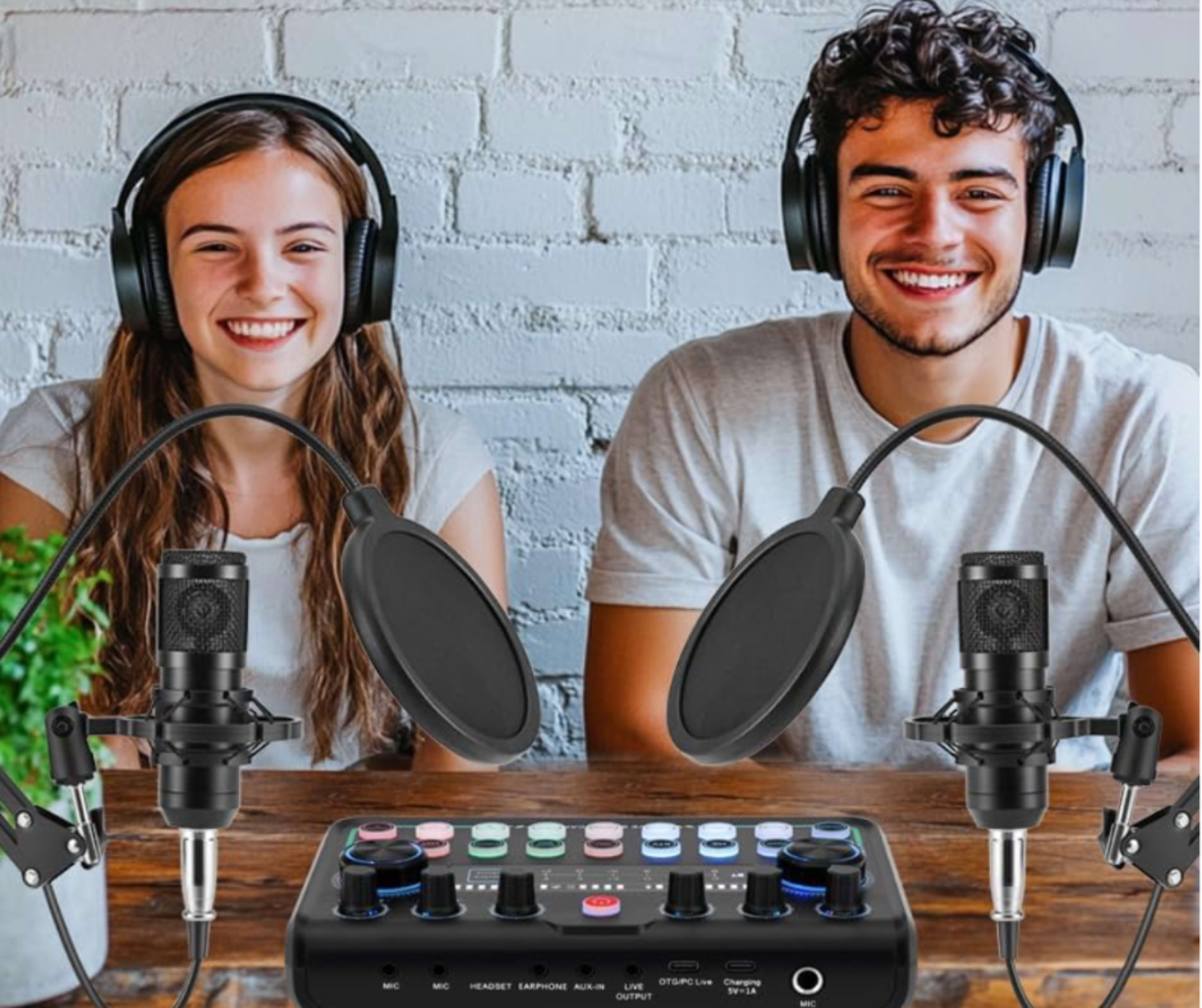 A young woman and a young man, both wearing headphones, smile while sitting in front of a recording setup with two microphones and an audio interface.
