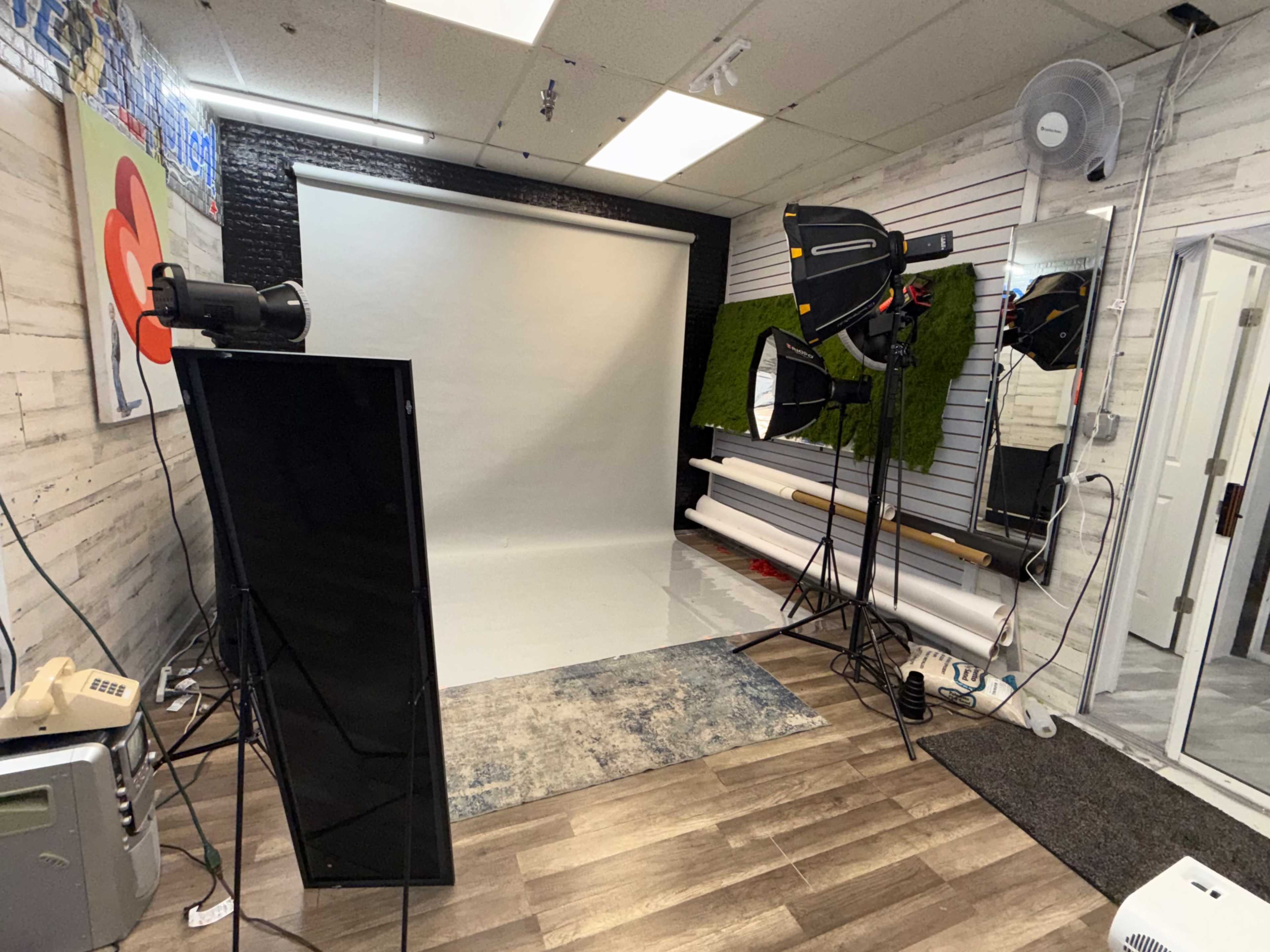 The image shows a photography studio equipped with lighting setups, a blank backdrop, and various props arranged neatly.
