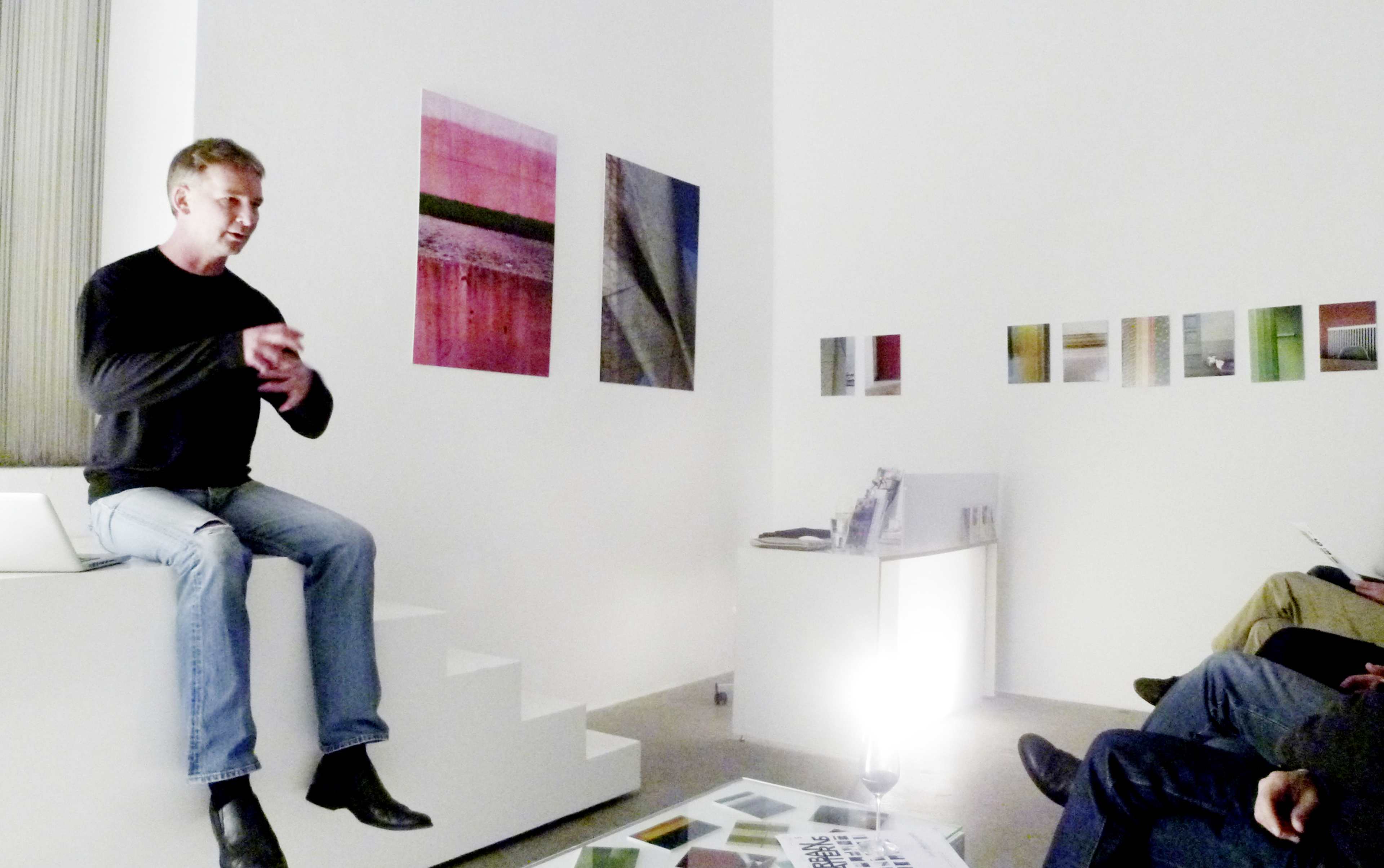 A speaker presents in an art gallery with abstract artworks hanging on the walls.