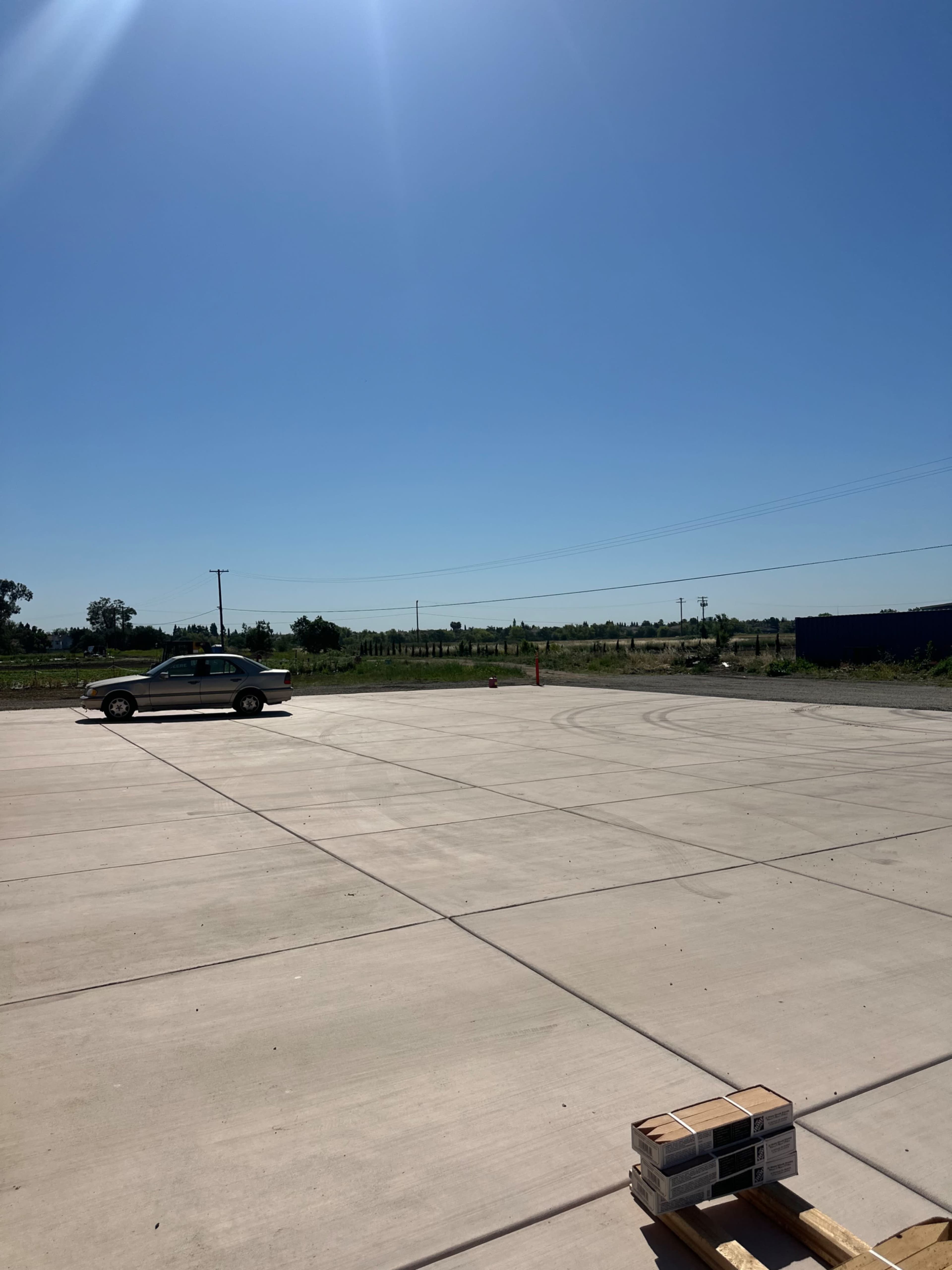 A car is parked on a large, empty concrete surface under a clear blue sky.