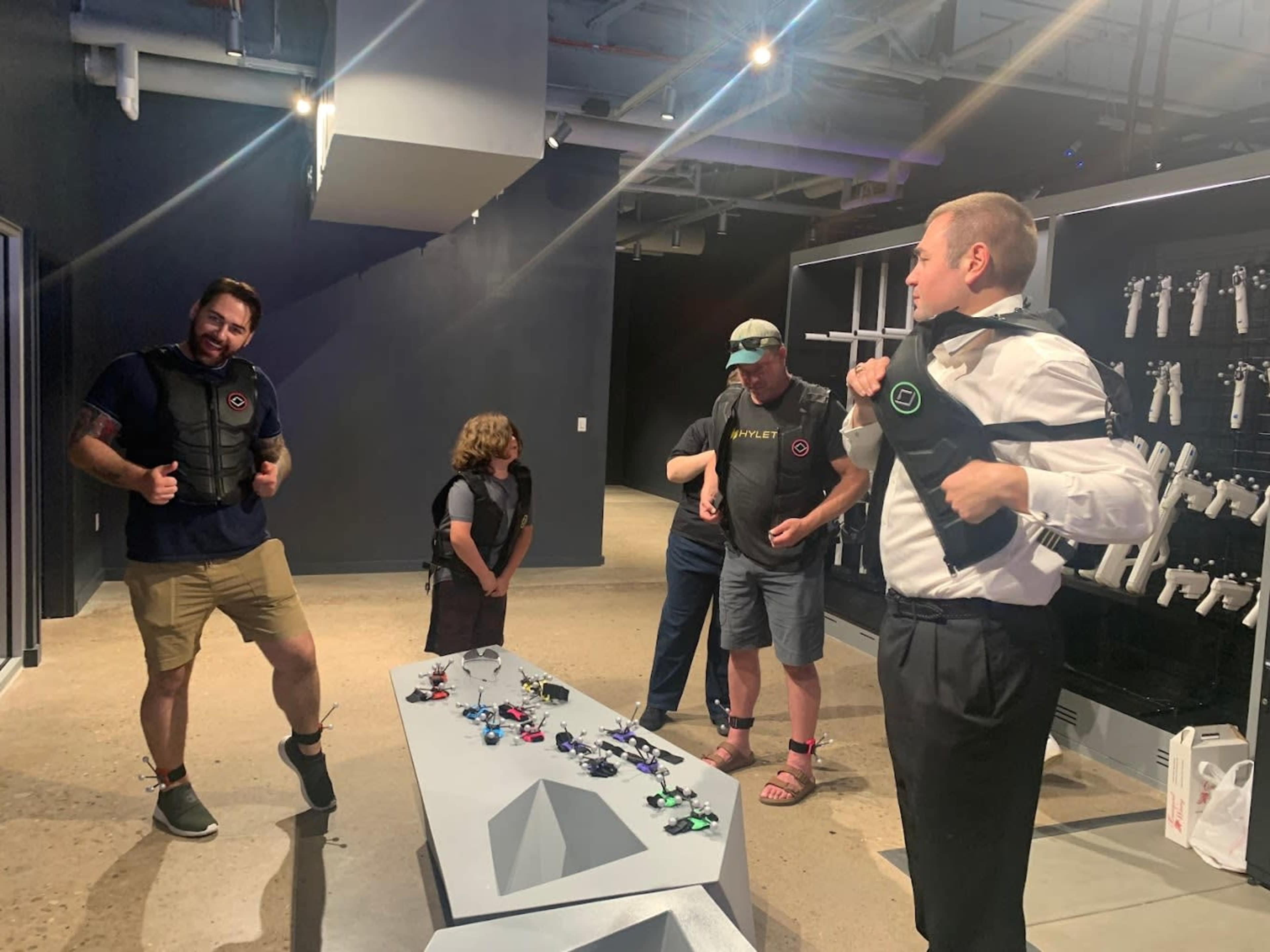 A group of five people is interacting in an activity center while wearing vests and preparing equipment on a table.