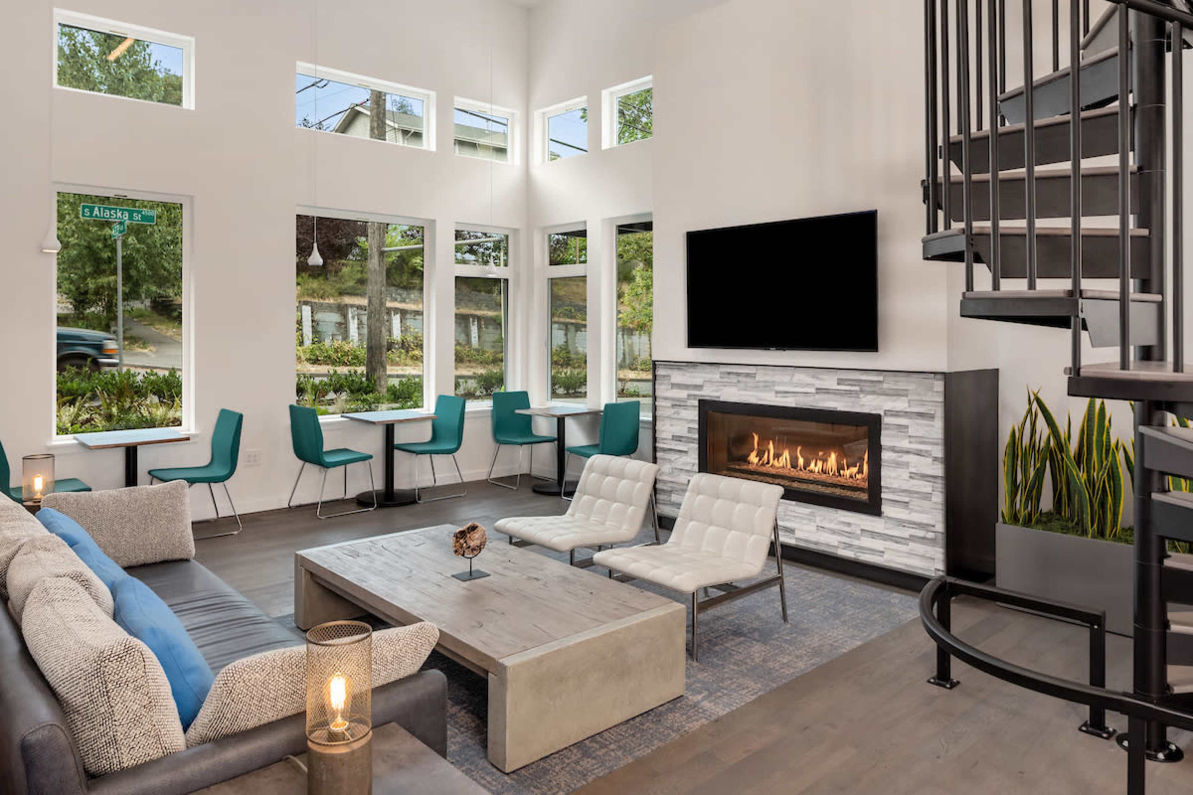 A modern living room with large windows, a fireplace, and a spiral staircase.
