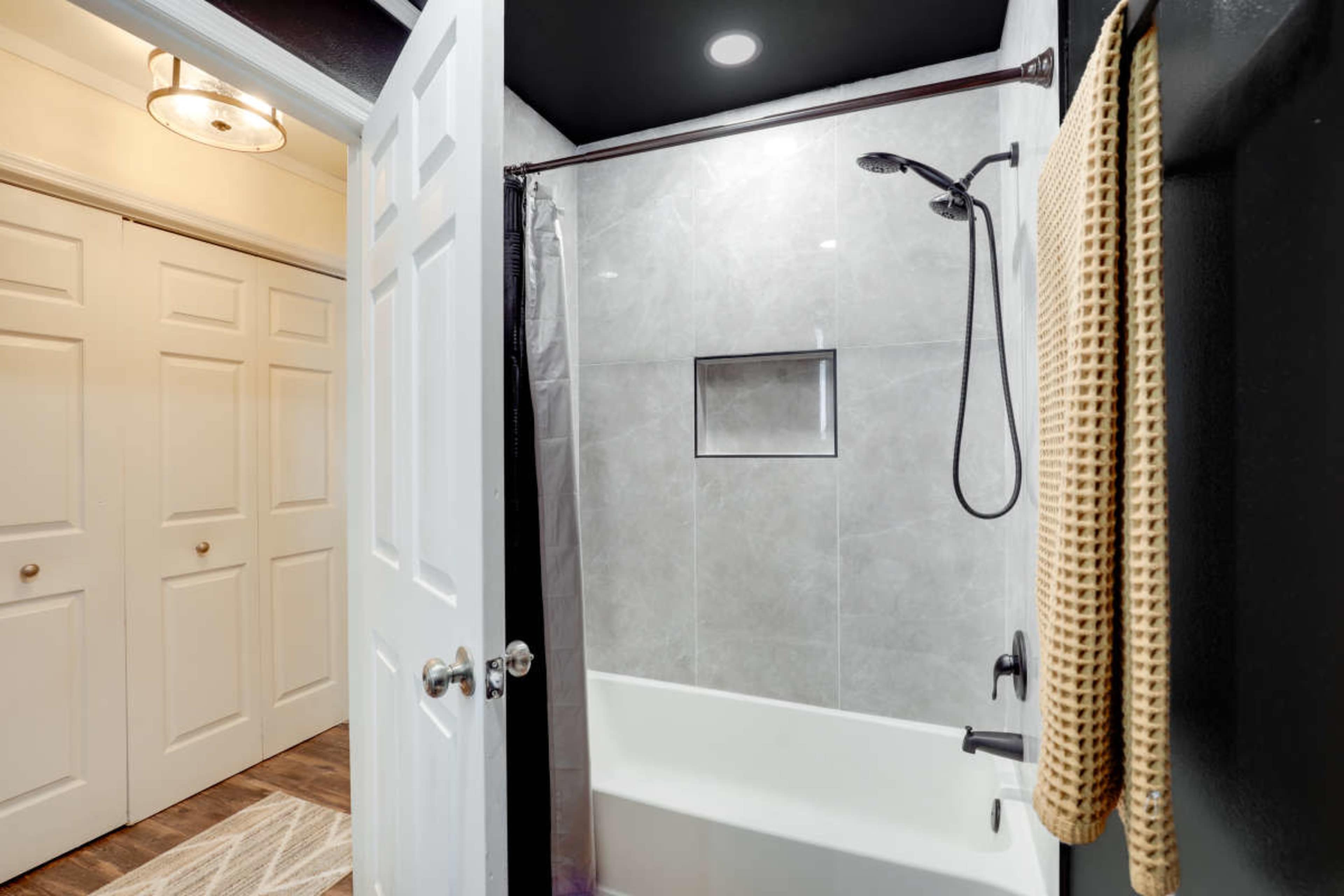 A modern bathroom with a glass-enclosed shower, a bathtub, and a towel hanging near the entrance.
