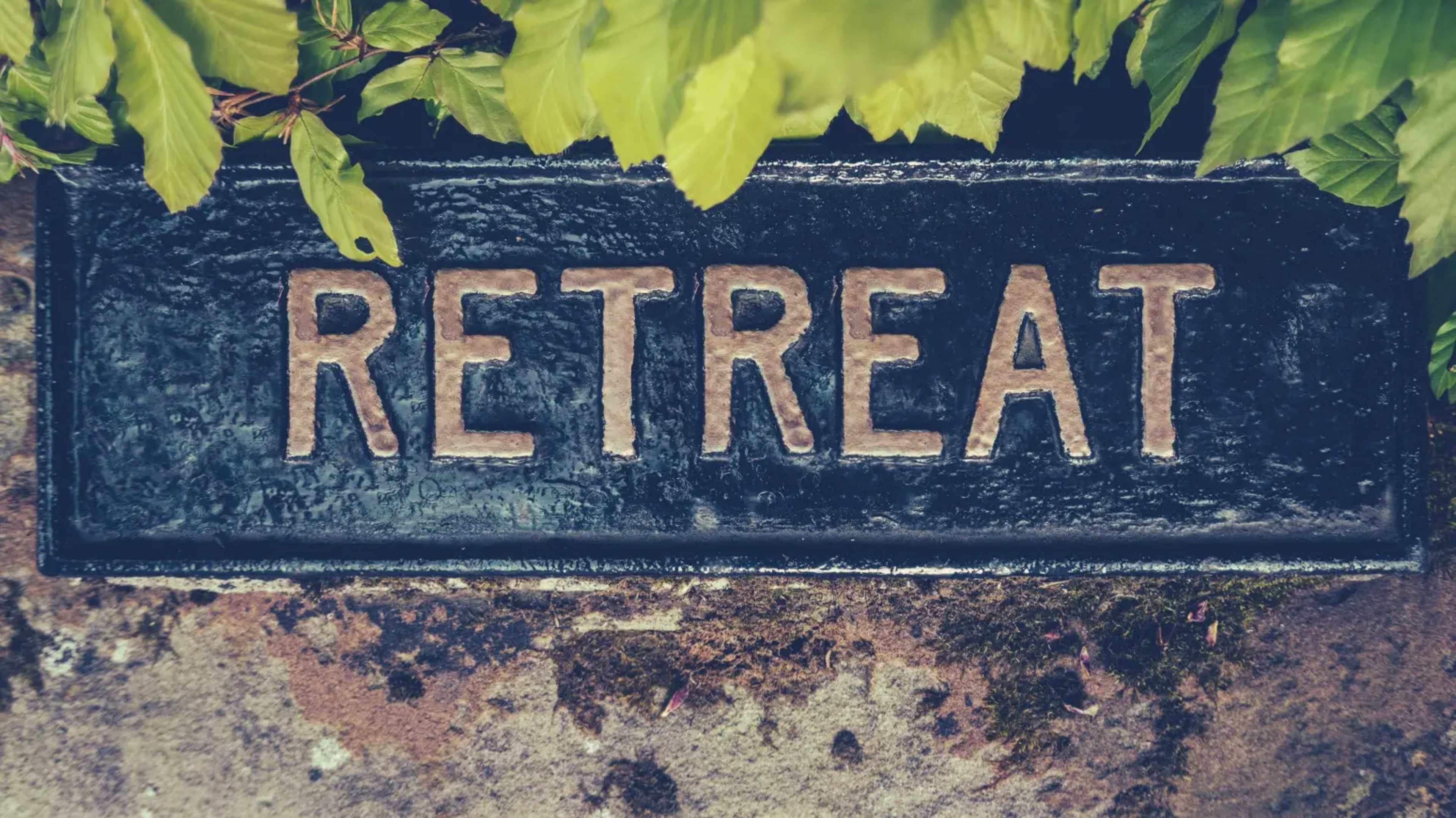 A sign reading "RETREAT" is partially obscured by green leaves.